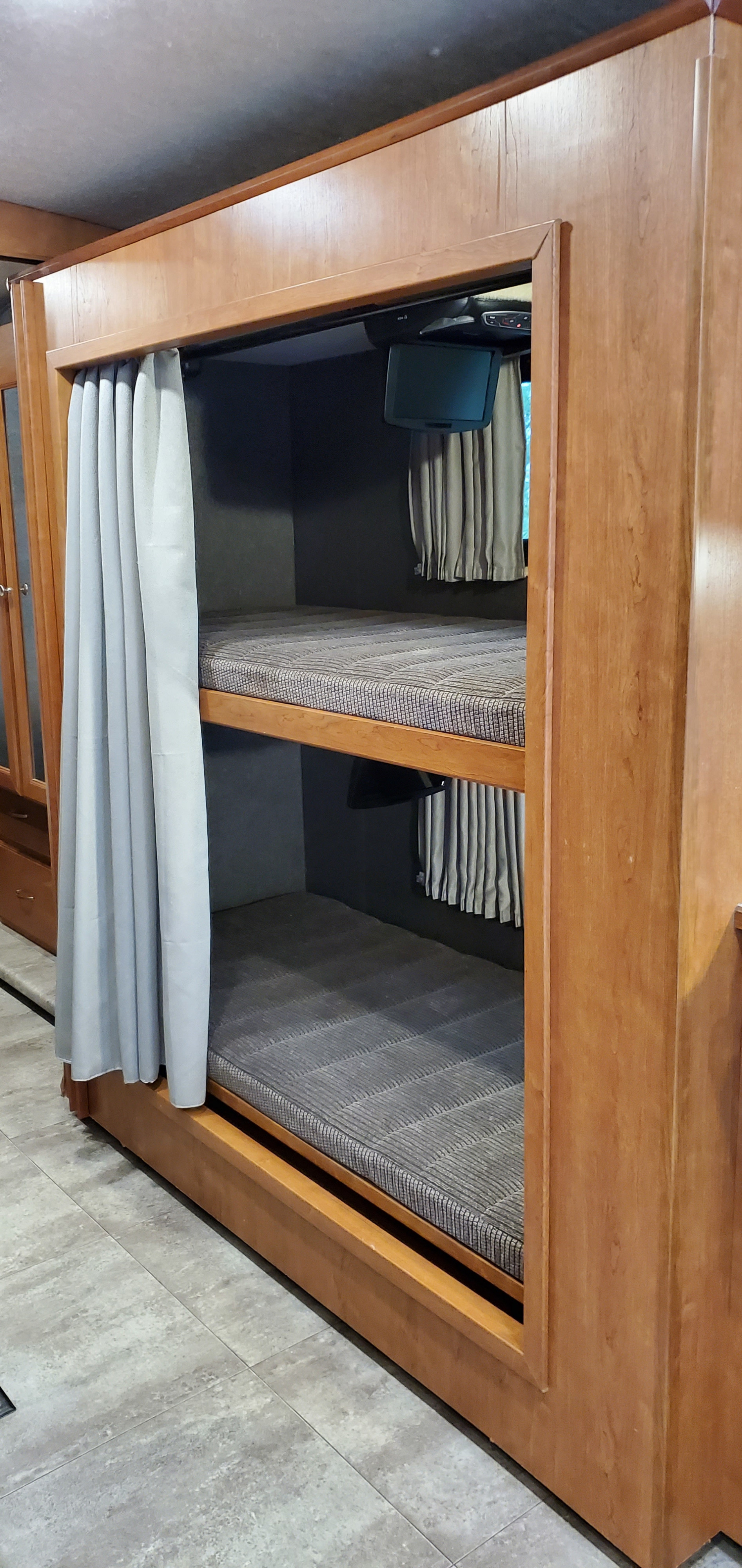 RV rental featuring built-in bunk beds with mattresses, privacy curtains, and individual TVs for cozy sleeping.. Winnebago Vista 2016