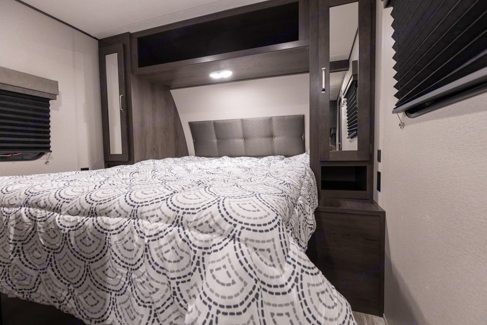 Step inside this RV rental's cozy bedroom, featuring a comfortable bed, padded headboard, and built-in storage cabinets.. Grand Design Transcend Xplor 261BH 2021