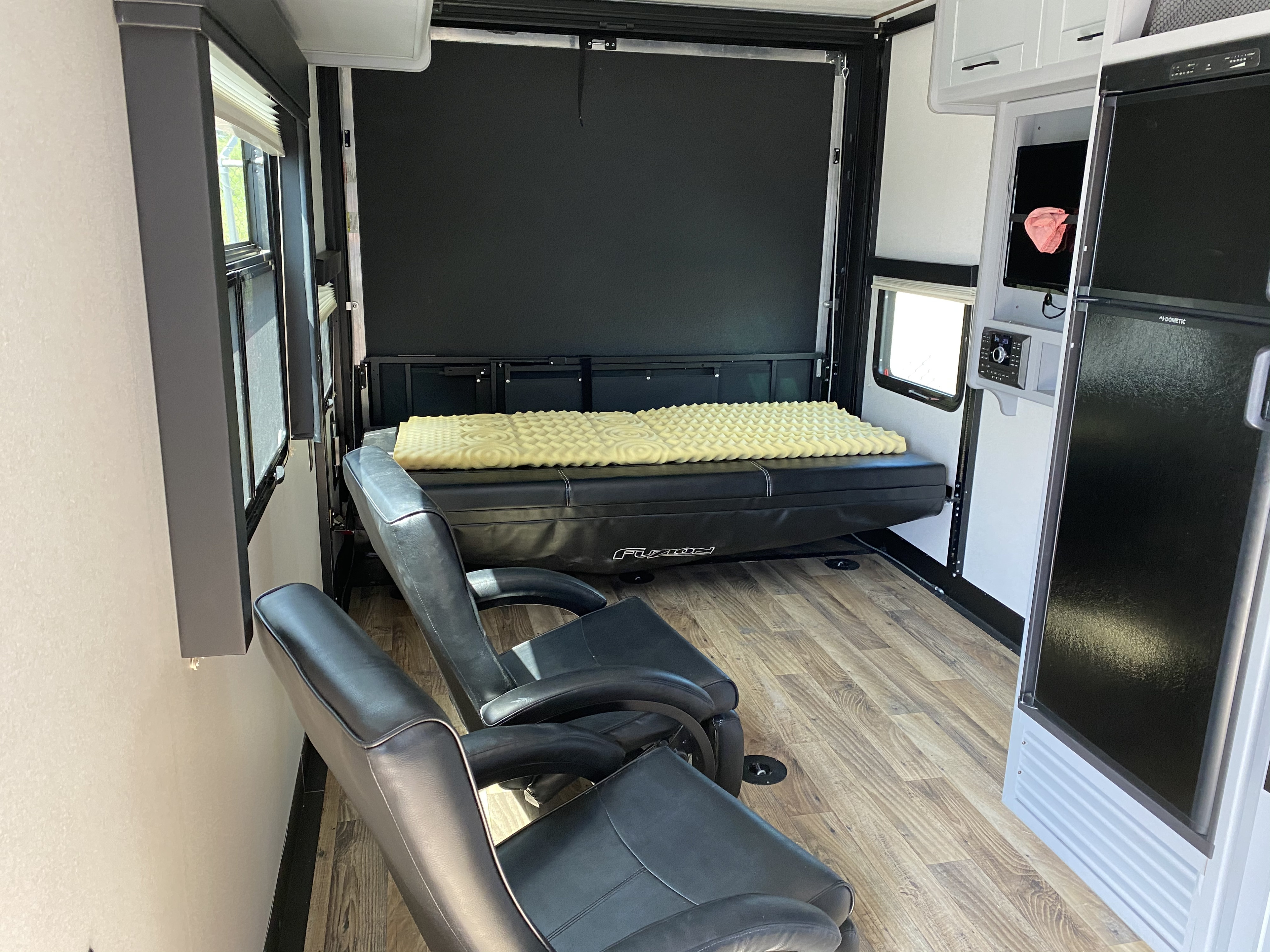 RV rental: Versatile toy hauler interior with recliners, convertible bed, TV, and fridge on wood floors.. Keystone Impact 2019