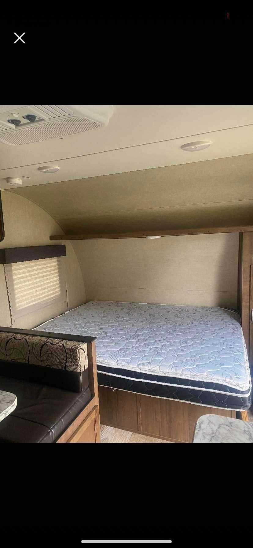 RV rental interior featuring a quilted mattress on a built-in bed and a cozy dinette area with seating and a table.. Gulf Stream Ameri-Lite 2019