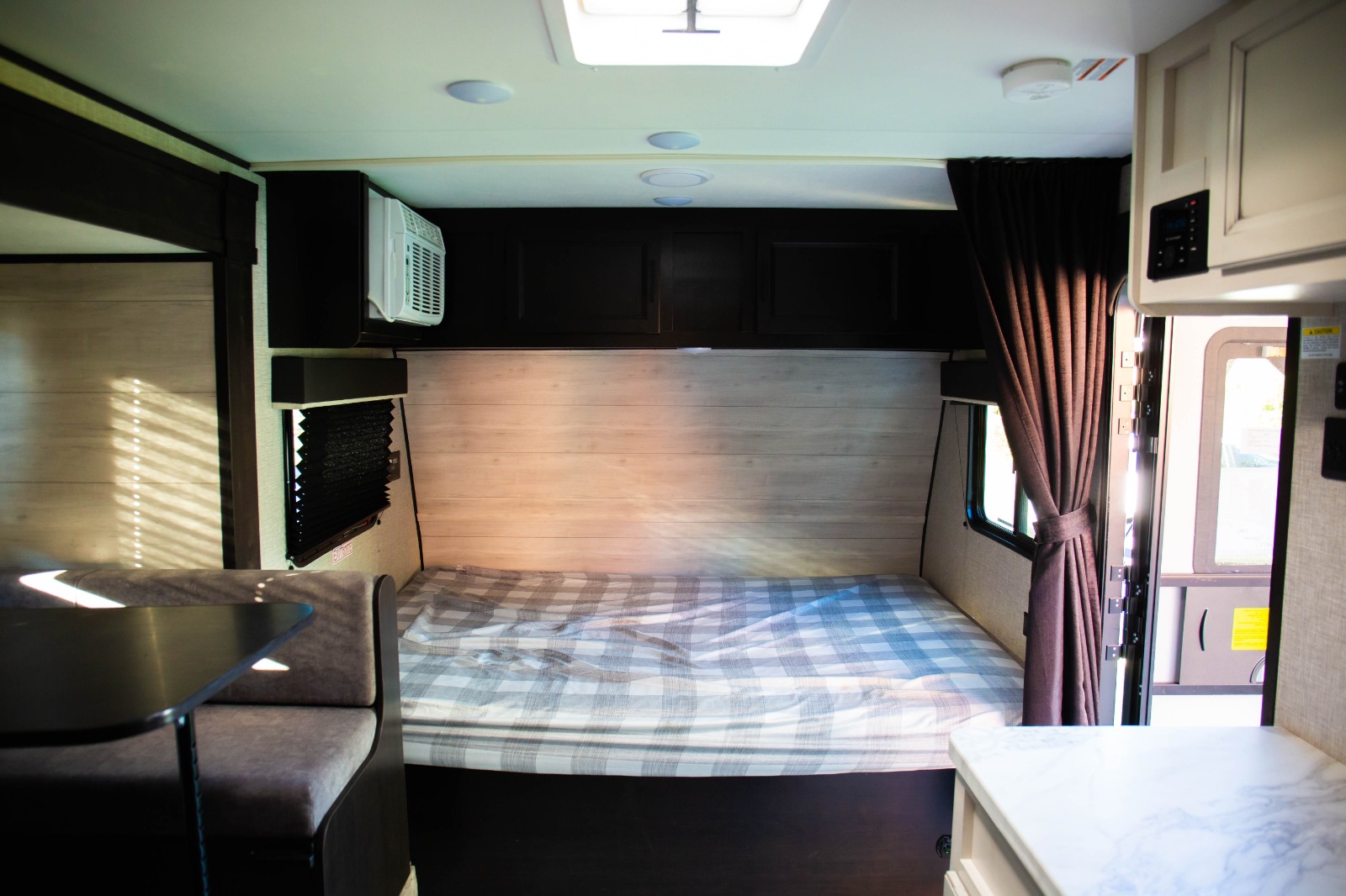 Comfortable RV rental interior with a plaid bed, dinette, and AC unit.. Jayco Jay flight slx 7 2022