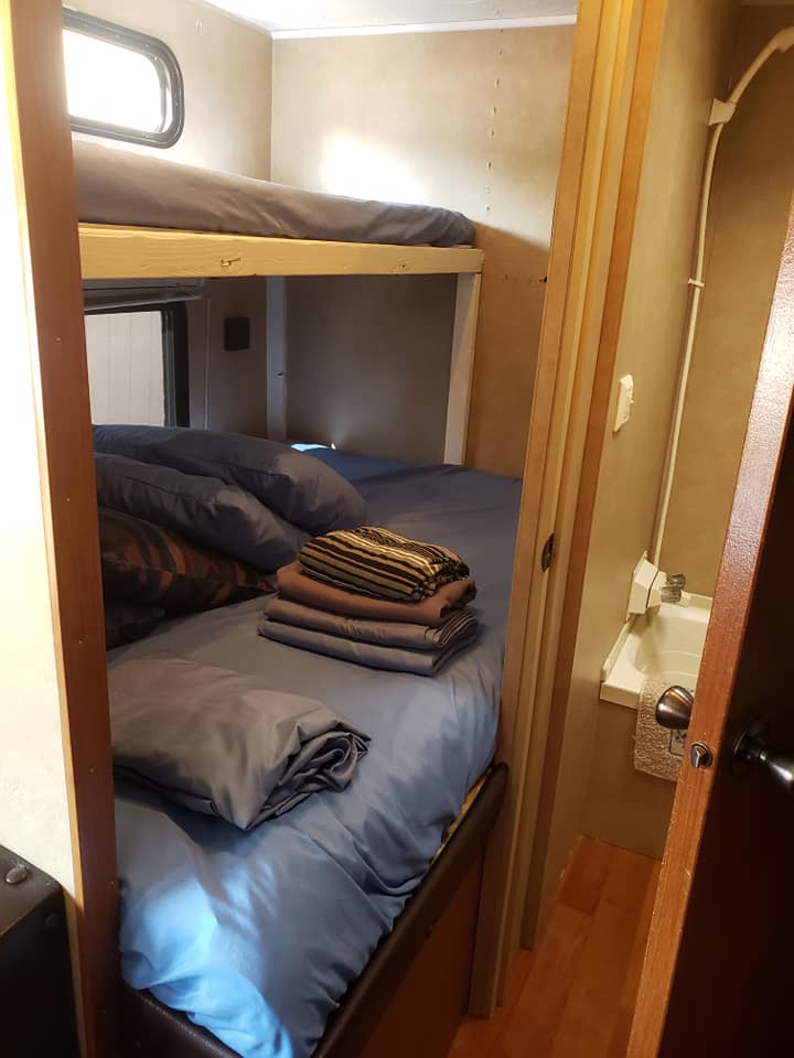 RV rental: Interior shows cozy bunk beds with blue bedding & stacked towels, leading to a compact bathroom.. Forest River Cherokee 2013