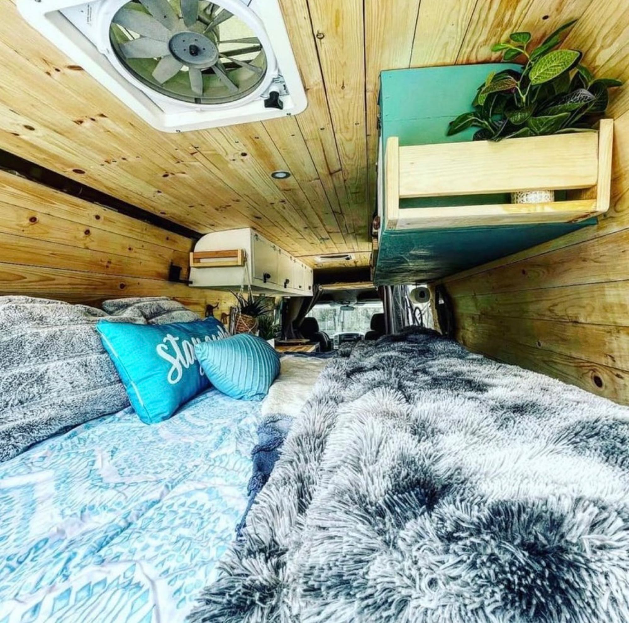 Experience cozy van life! This rustic RV rental interior boasts wooden walls, comfy bed, and integrated storage, ideal for your journey.. Freightliner Sprinter 2010