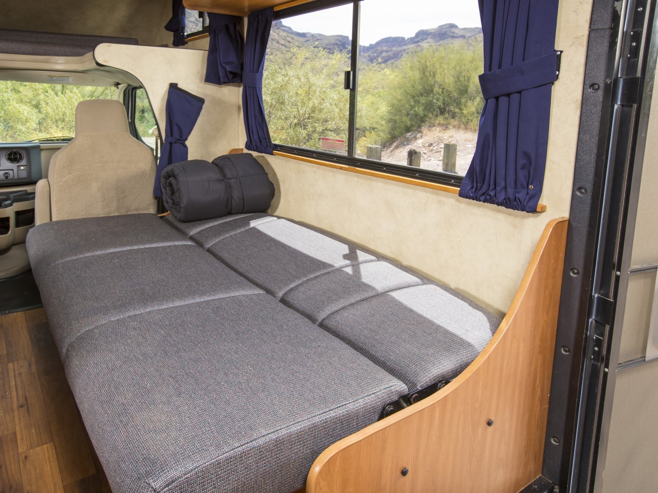 RV rental interior: a comfy convertible bed with a rolled sleeping bag, offering scenic outdoor views for travel.. Thor Majestic 2013