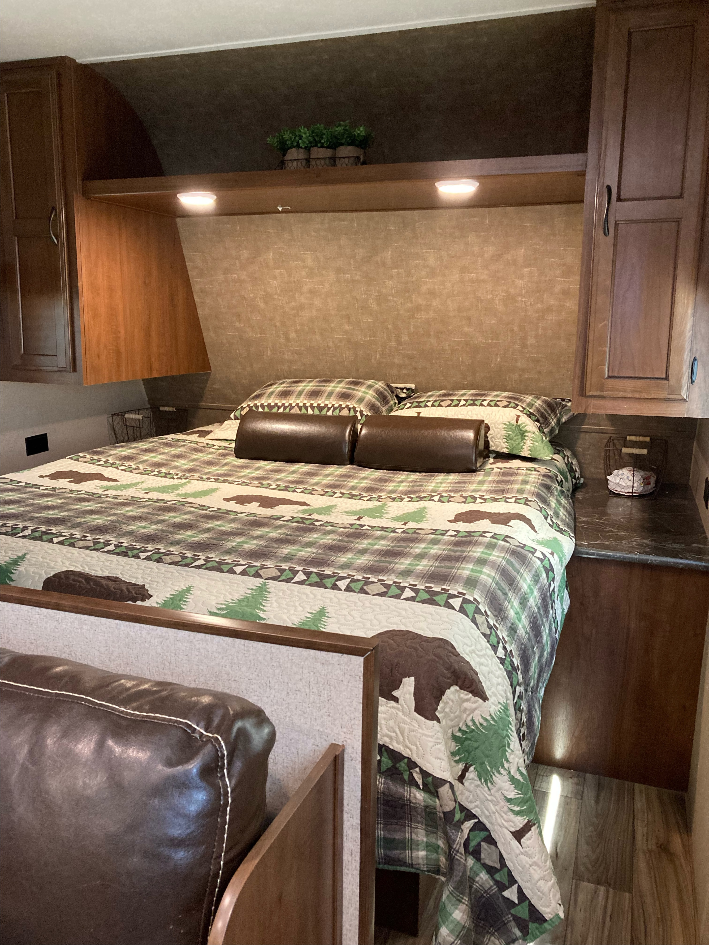 Cozy RV rental bedroom with a rustic plaid and bear-themed bed, overhead lighting, and convenient storage.. Jayco Jay Flight SLX 2016