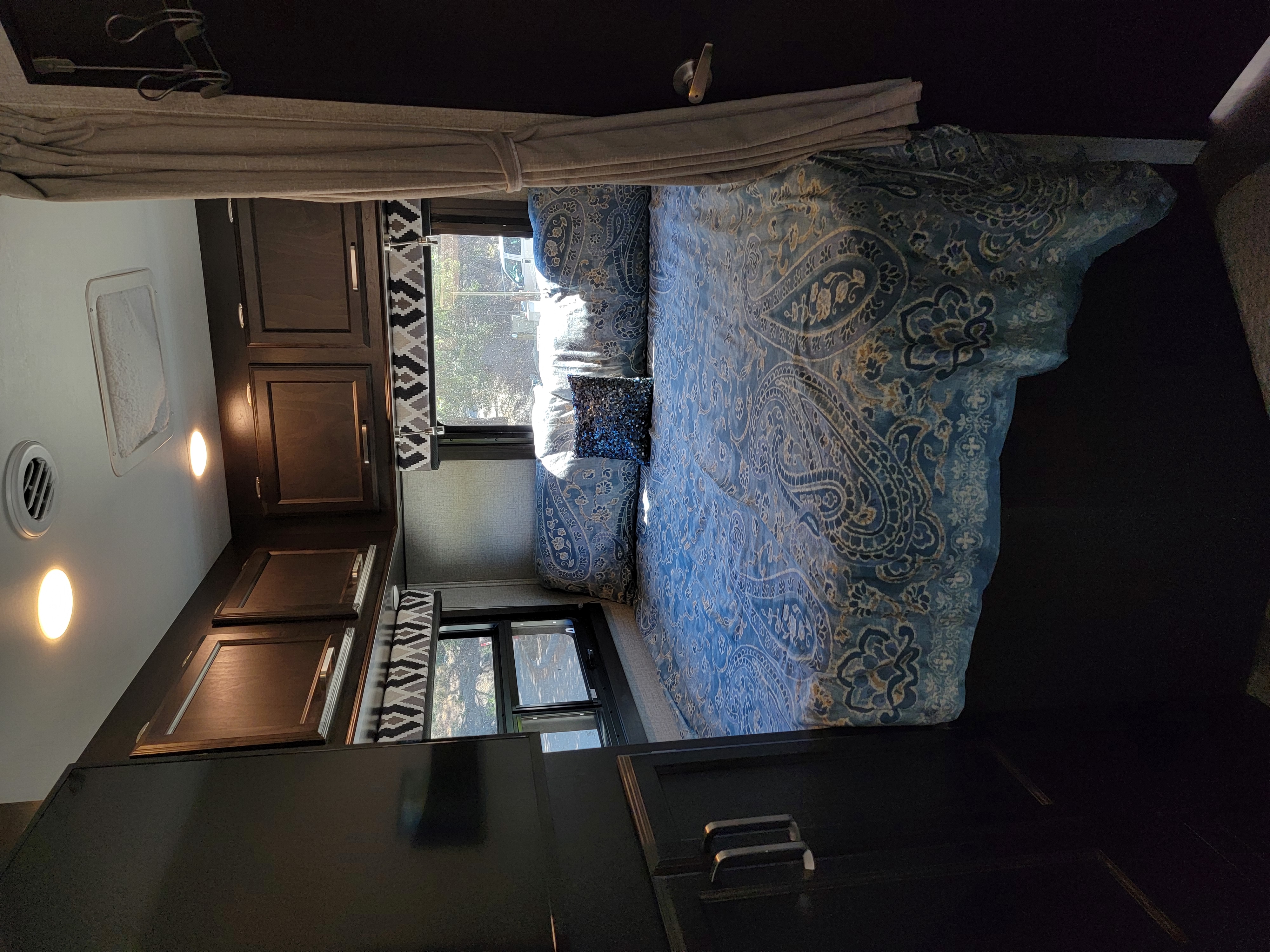 Cozy RV rental bedroom with blue paisley bedding & dark wood cabinets.. Entegra Coach Odyssey 2021