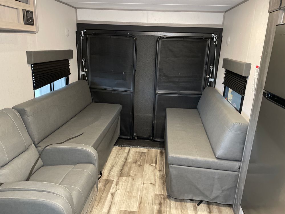 RV rental interior with two gray sofas, wood-look floor, and large rear access doors, perfect for cargo.. Coleman 270TQ 2022