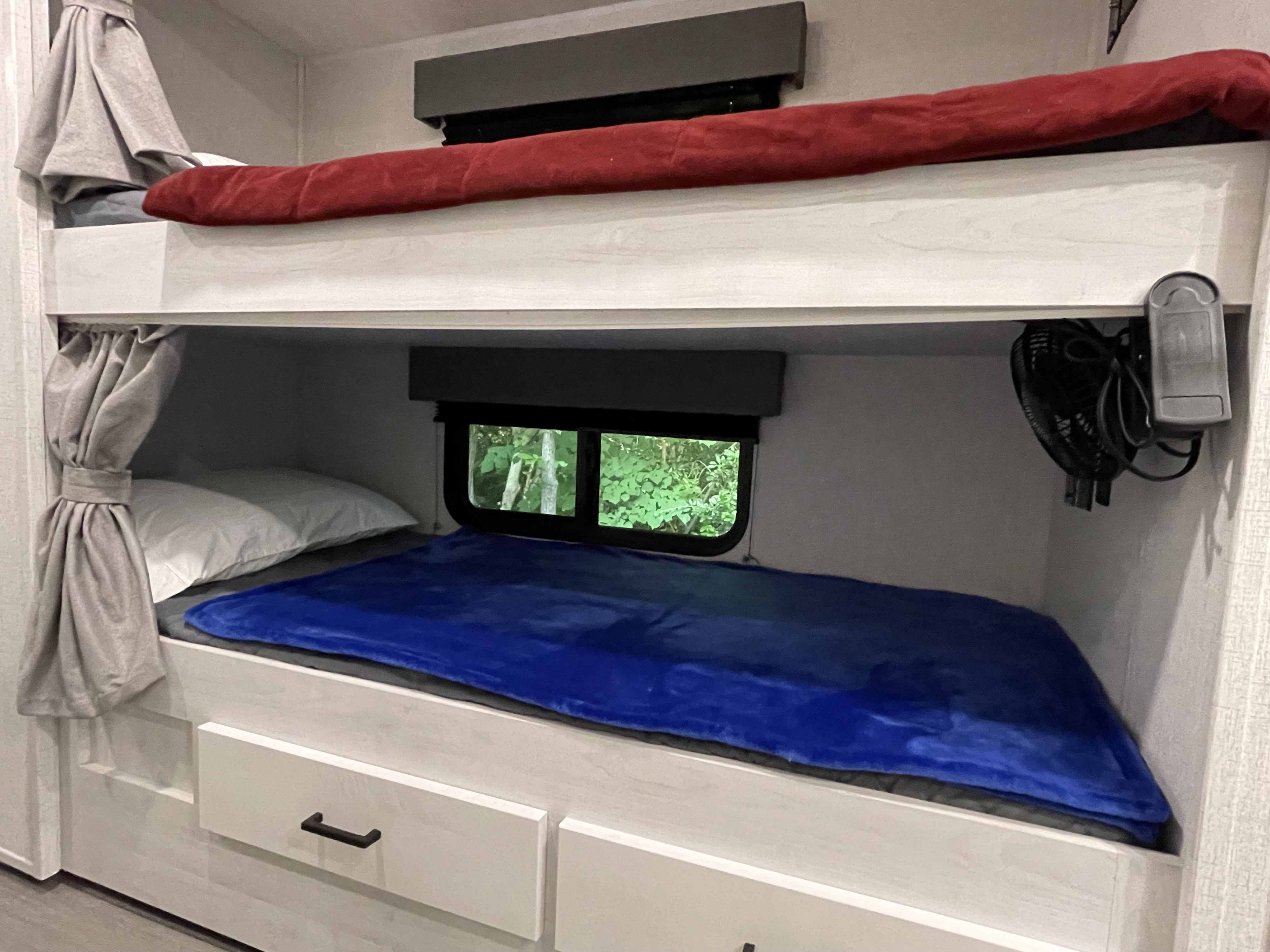 Cozy RV rental bunk beds, perfect for family adventures. Features windows, curtains, and built-in storage drawers.. East to West Entrada 3100FB 2022