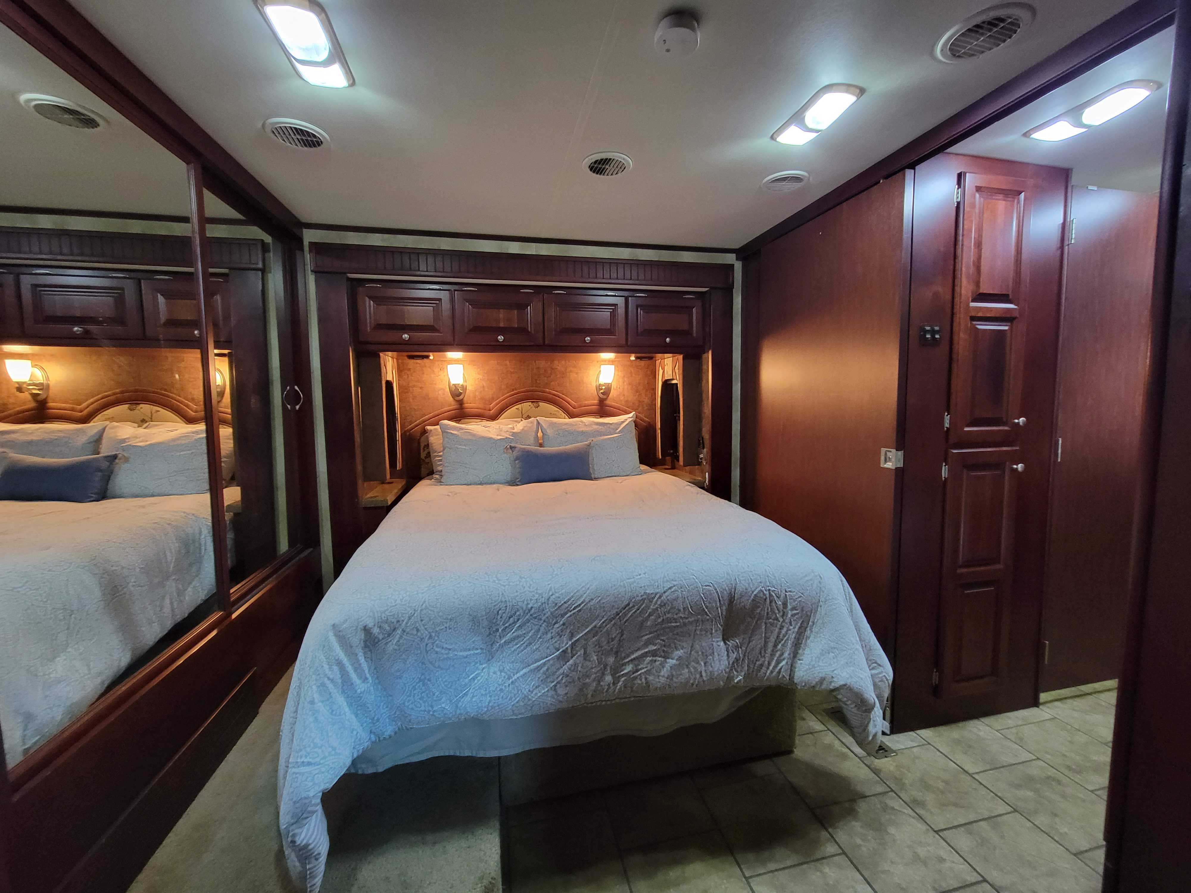 Comfortable RV rental bedroom featuring a spacious bed, warm lighting, and ample wood cabinetry—ideal for mobile living.. Allegro Allegro Red 2011