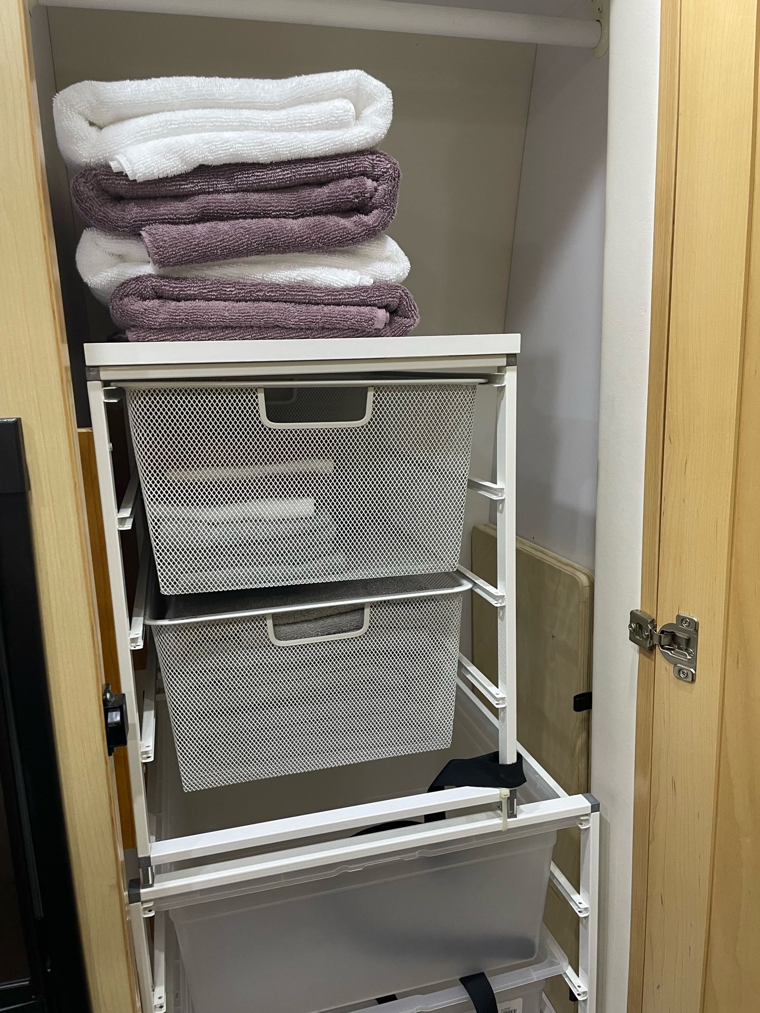 Efficient RV rental storage: towels stacked above pull-out mesh and plastic bins within a cabinet.. Pleasure-Way Pleasure-Way Class B 2012