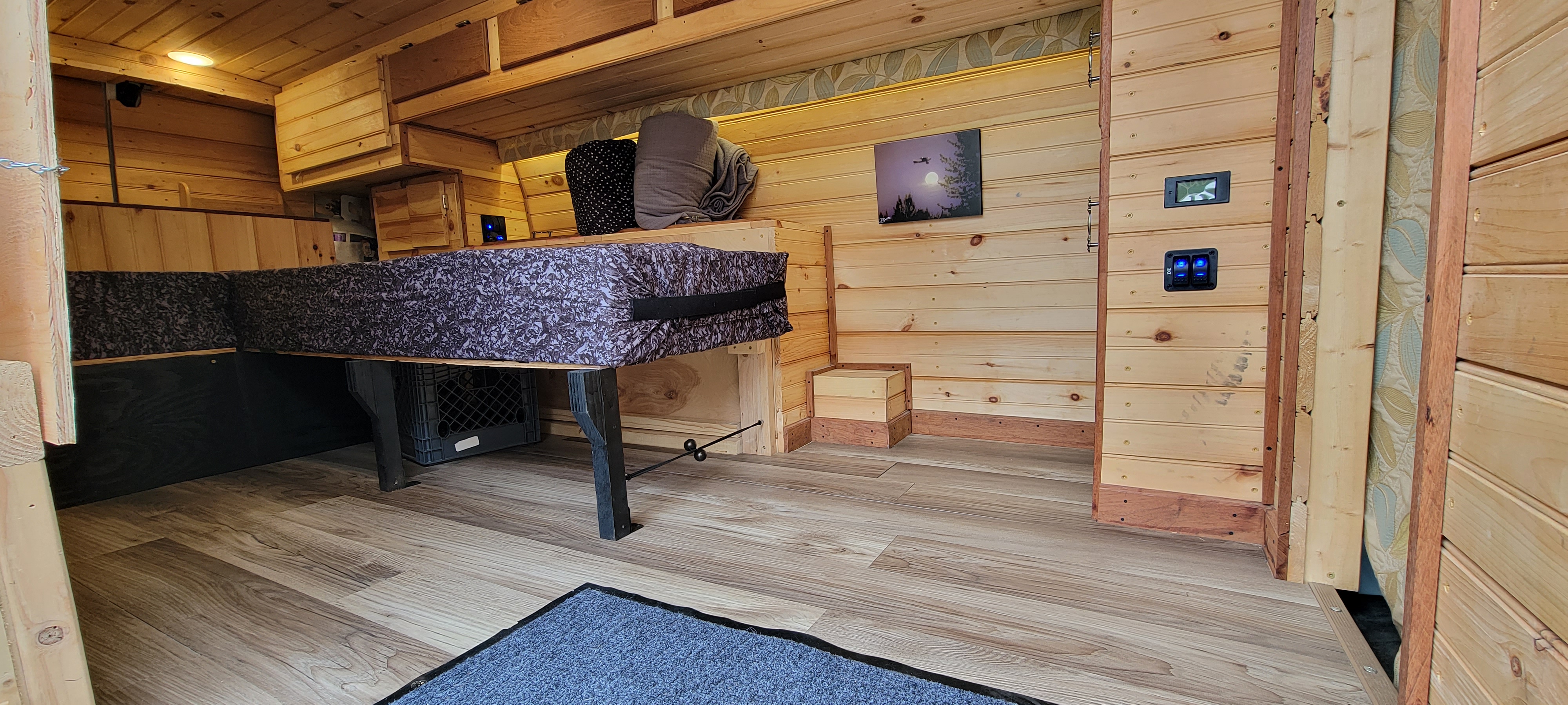 This RV rental features a beautiful custom wooden interior, compact bed/seating, and integrated controls for a cozy travel experience.. GMC Savanna 2014