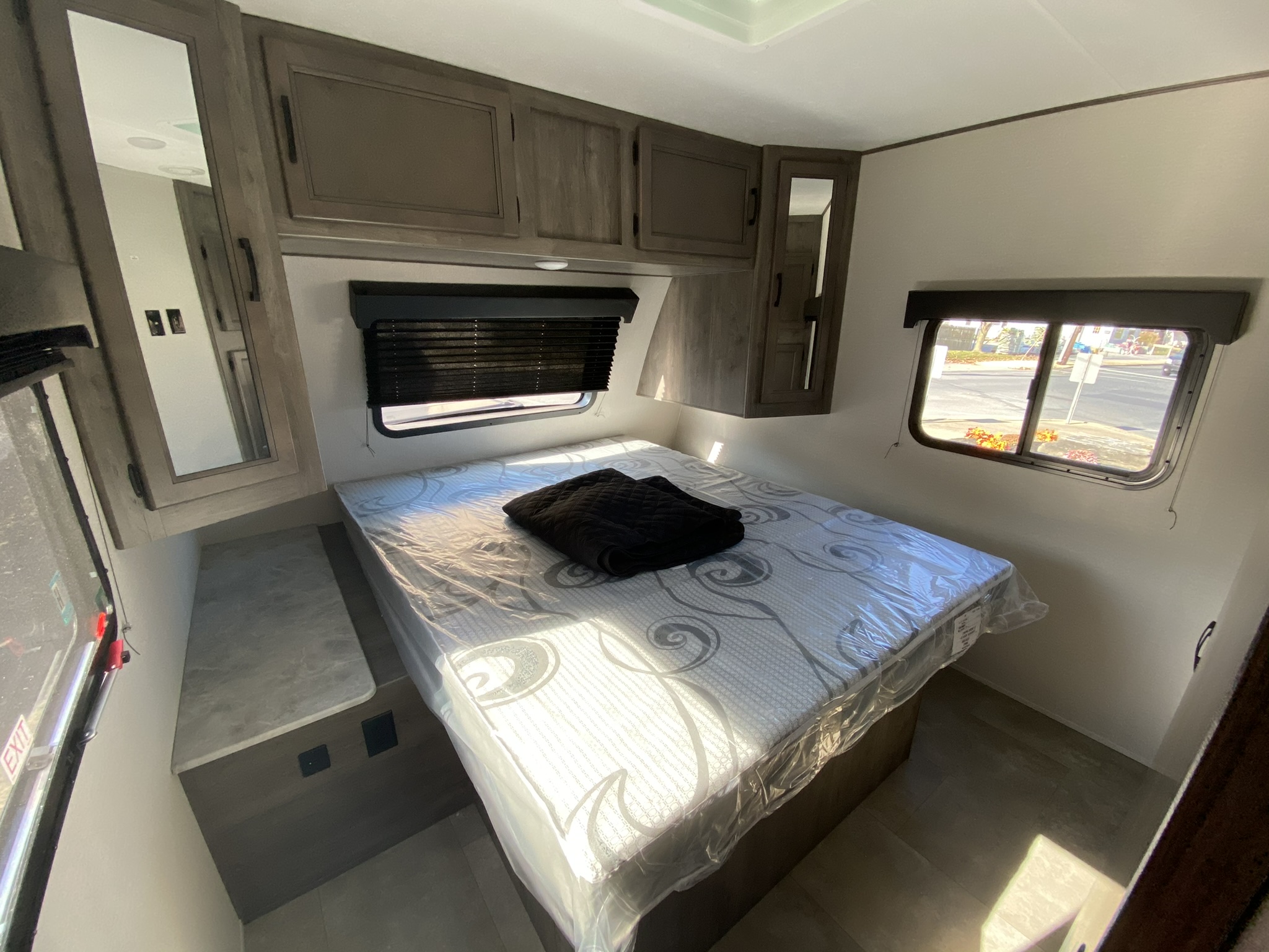 Clean RV rental bedroom with a fresh mattress, ample storage cabinets, and a bright window view.. Coachmen Apex 2021