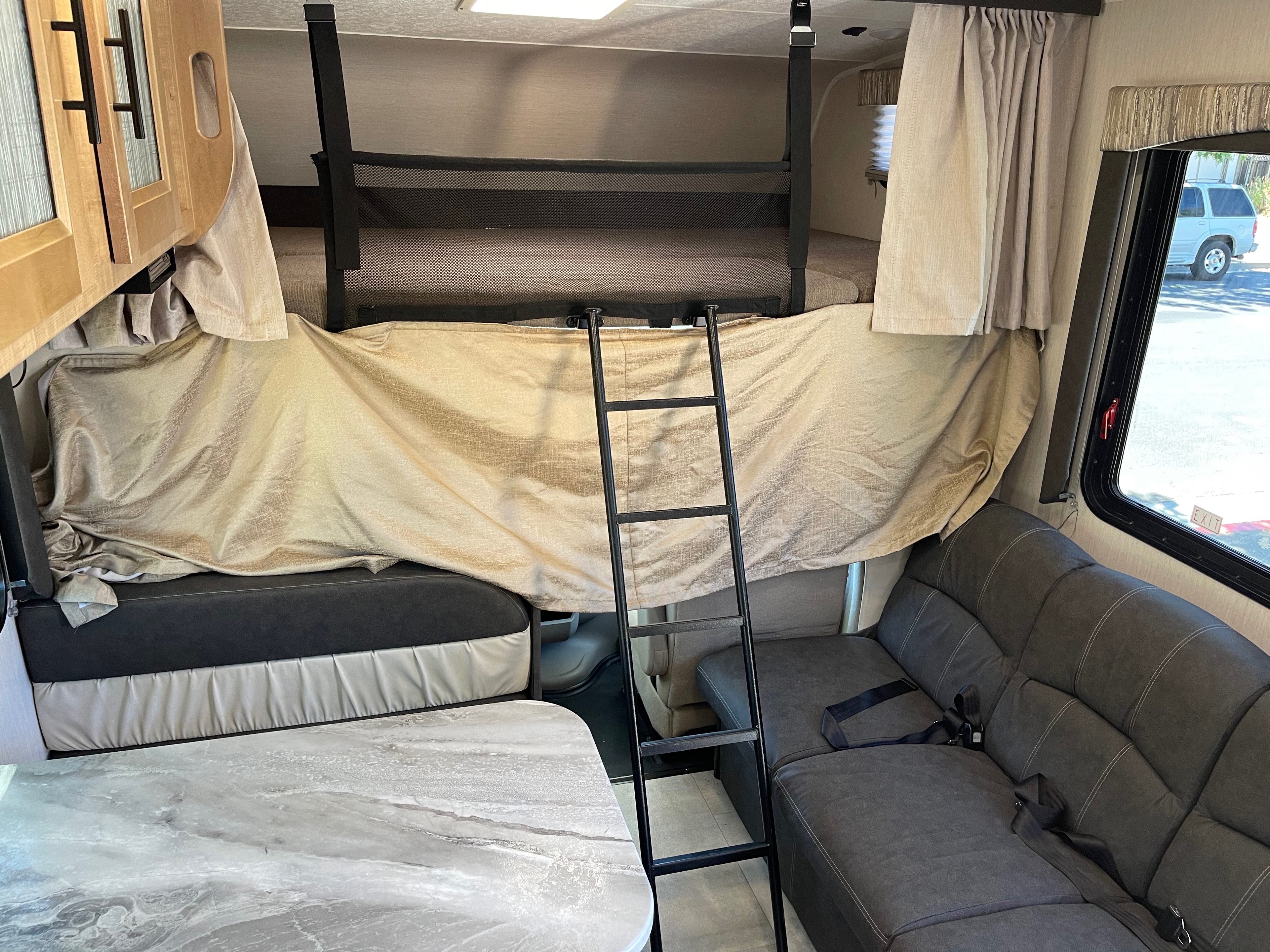 Step inside this RV rental: Features include a bunk bed, safety net, ladder, and a cozy dinette & sofa setup.. Coachmen Leprechaun 2021