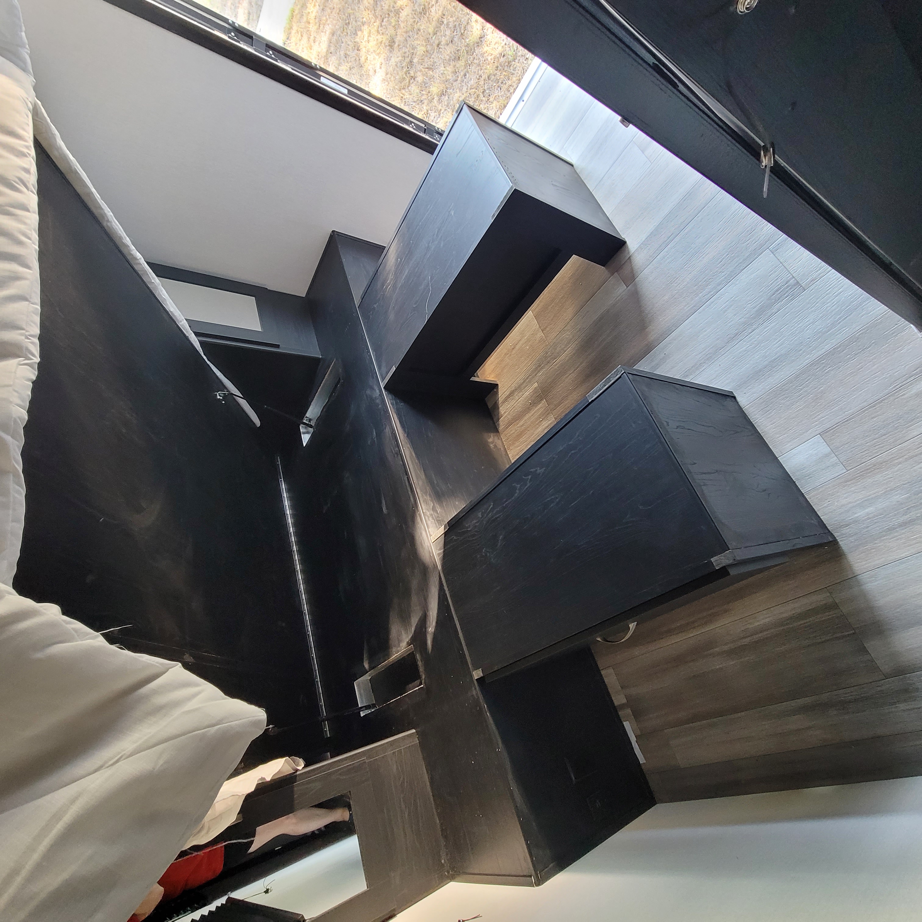 Modern RV rental interior with sleek black cabinetry, wood flooring, and a bed. Compact and stylish design.. Forest River Coachmen Freedom Express Ultra Lite 2022