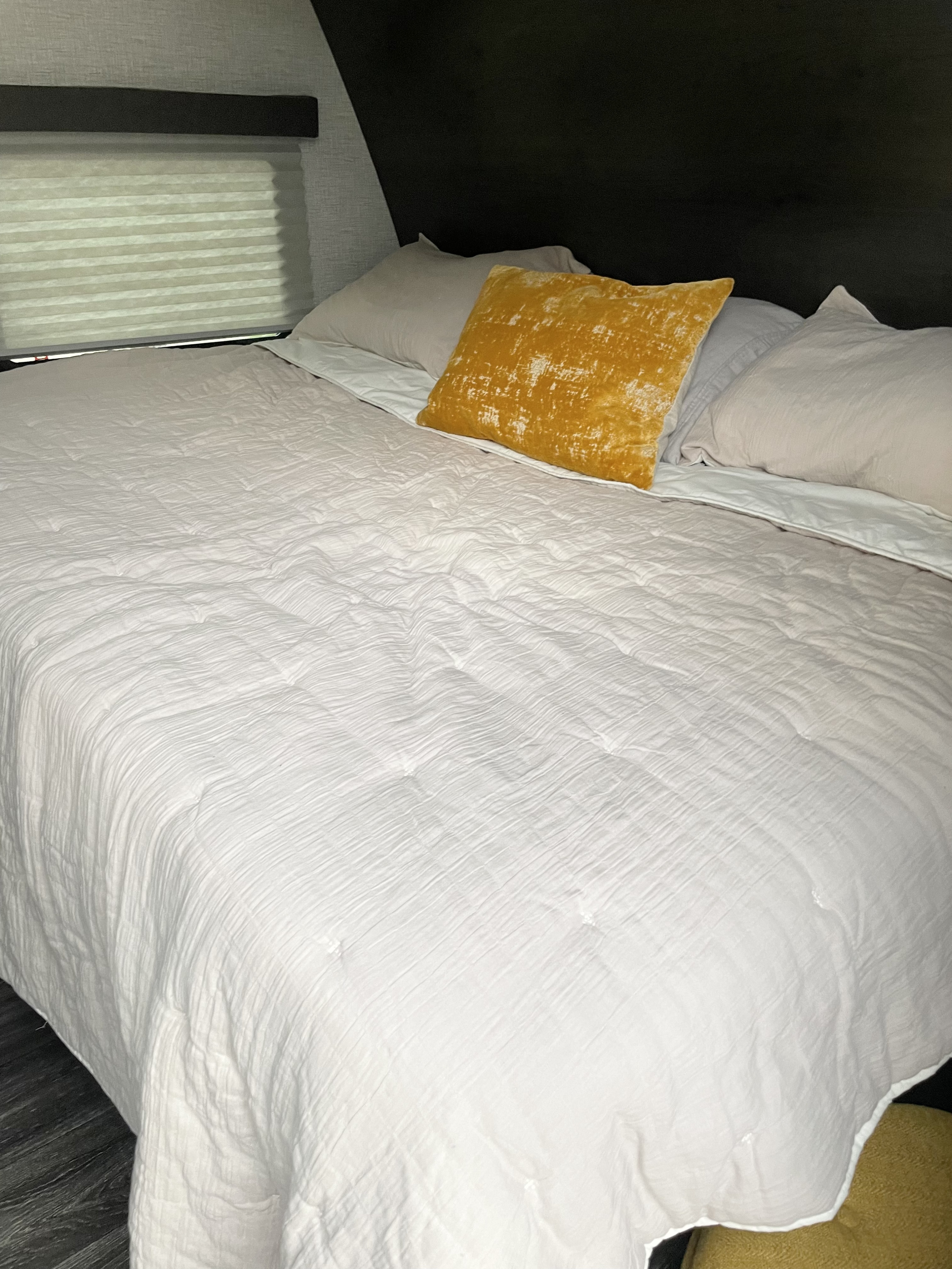 Cozy RV rental bed with white comforter & yellow pillow. Perfect for a comfortable stay.. Keystone RV Bullet Crossfire 2021