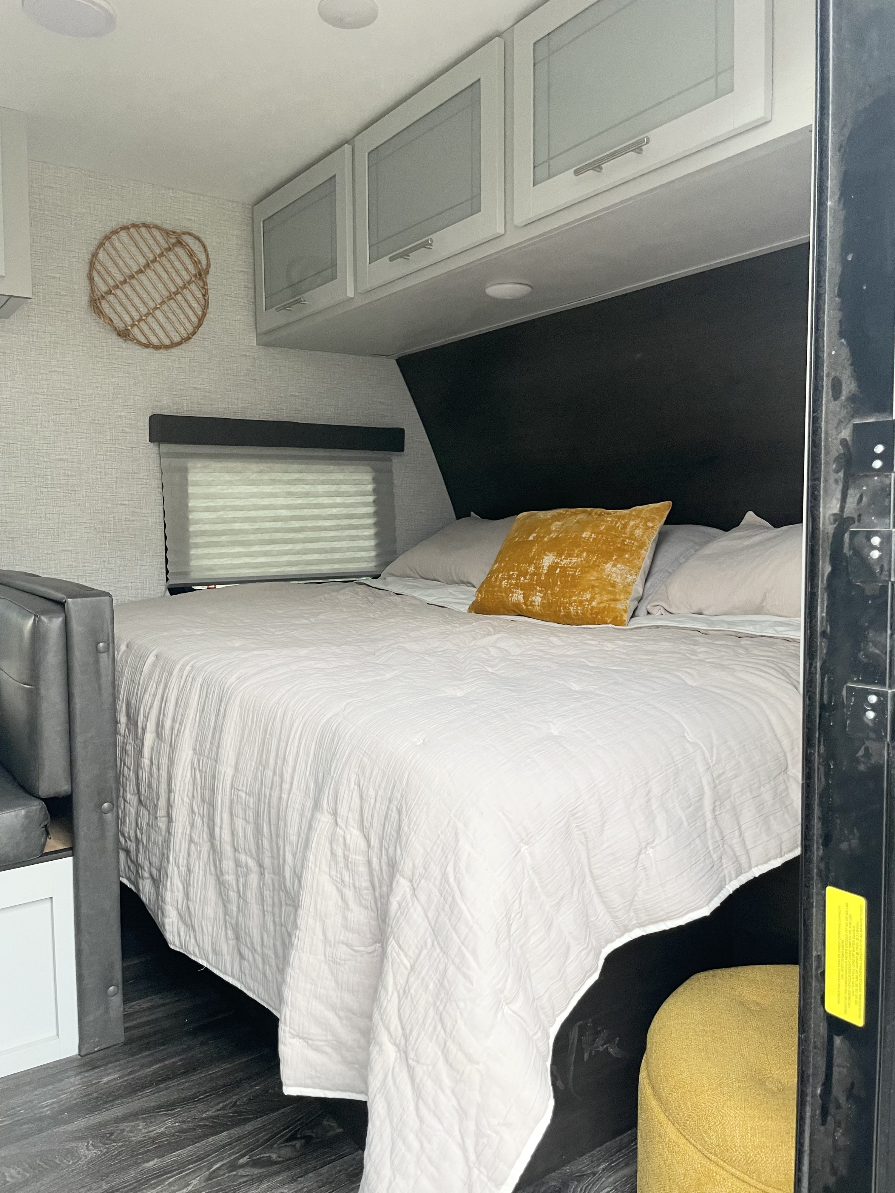 RV rental bedroom: comfortable bed with white bedding, a yellow accent pillow, practical overhead storage, and window.. Keystone RV Bullet Crossfire 2021