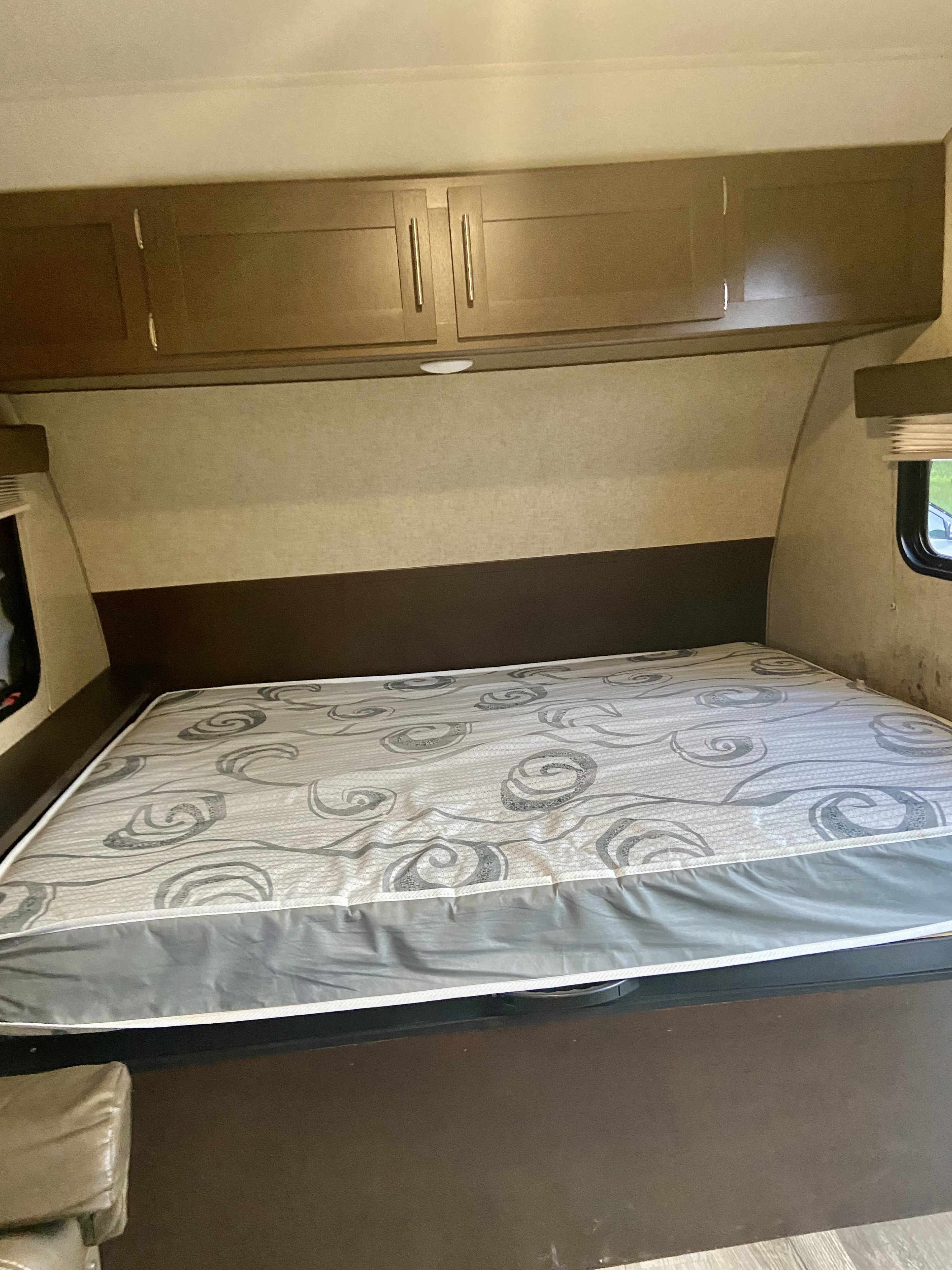 RV rental bedroom featuring a comfortable bed, overhead cabinets, and soft lighting for a relaxing stay.. Forest River Cherokee Wolf Pup 2018