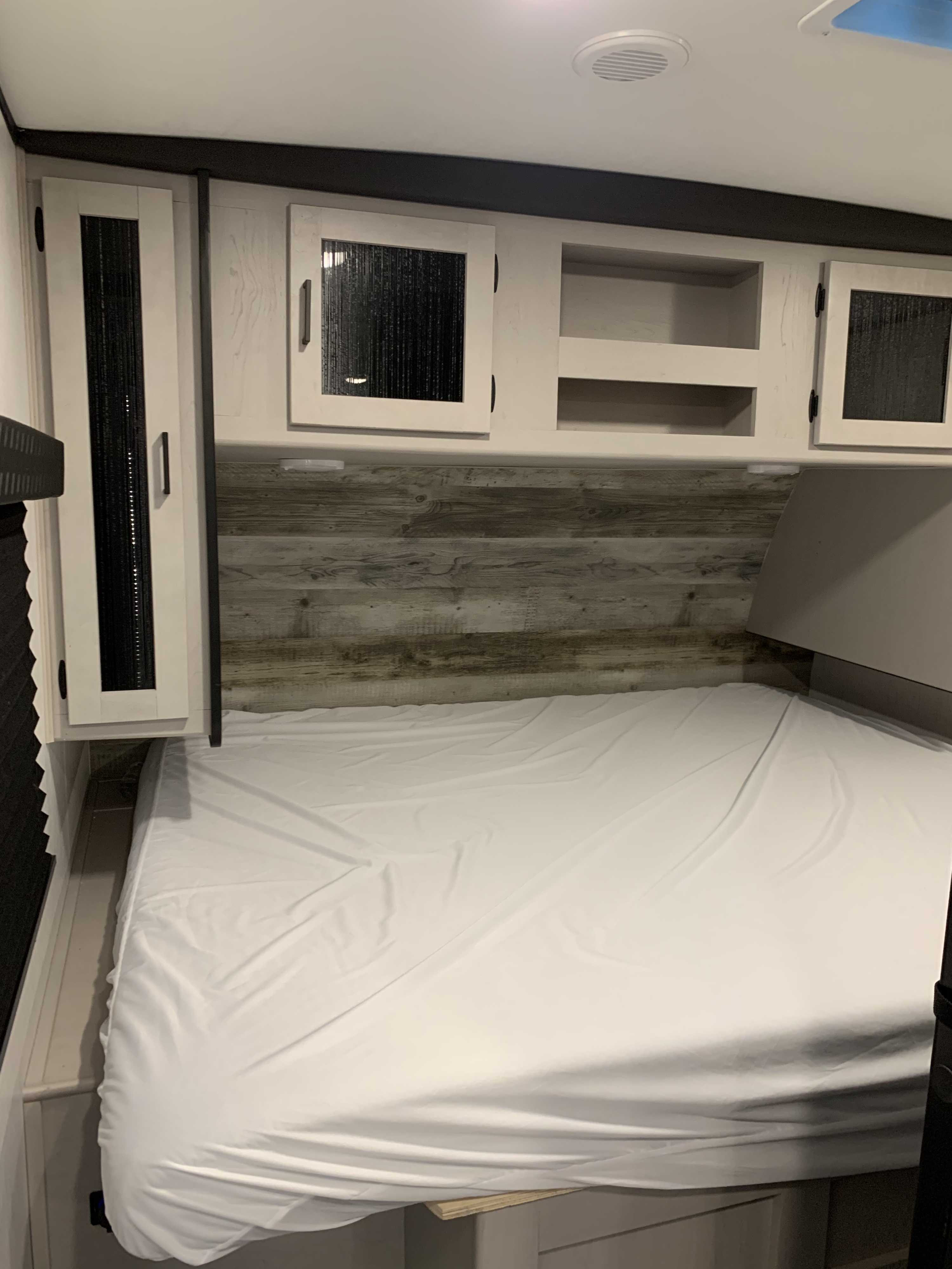 Experience comfort in this cozy rv rental bedroom. Features a clean bed, modern wood-look headboard, and storage cabinets.. Heartland RVs Mallard 2022