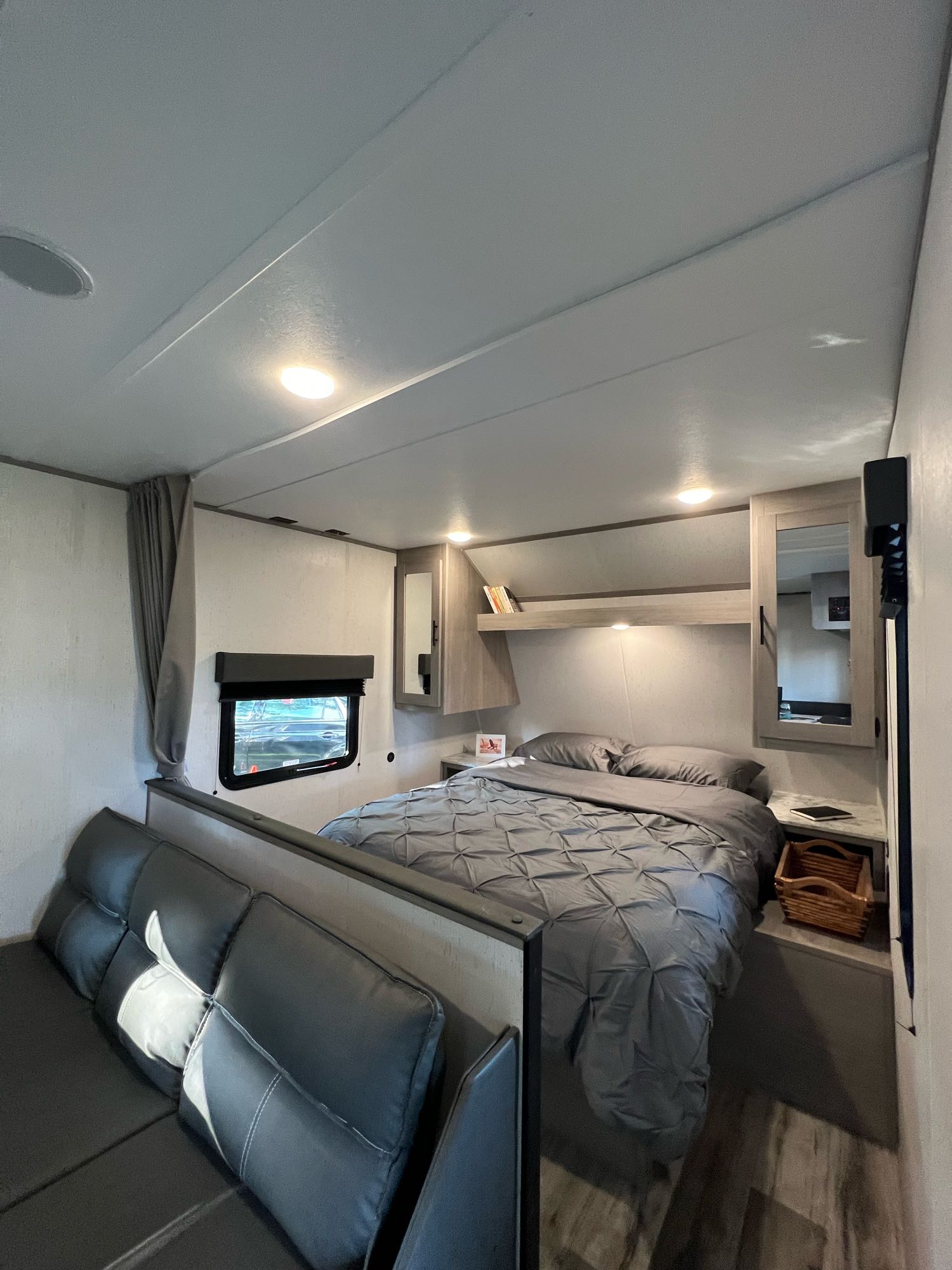 Explore this cozy RV rental's interior, featuring a bed with grey bedding, a comfy sofa, and practical overhead storage.. Dutchmen Coleman Lantern LT 2022