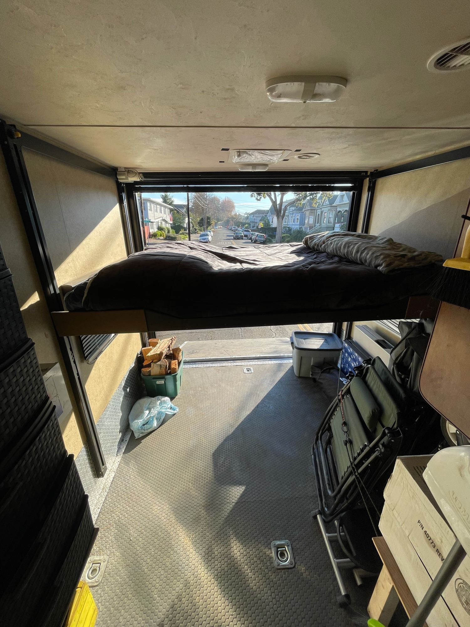 This RV rental's versatile interior features a raised bed over its cargo area, offering a mobile living space with street views.. Forest River X-Lite 2015