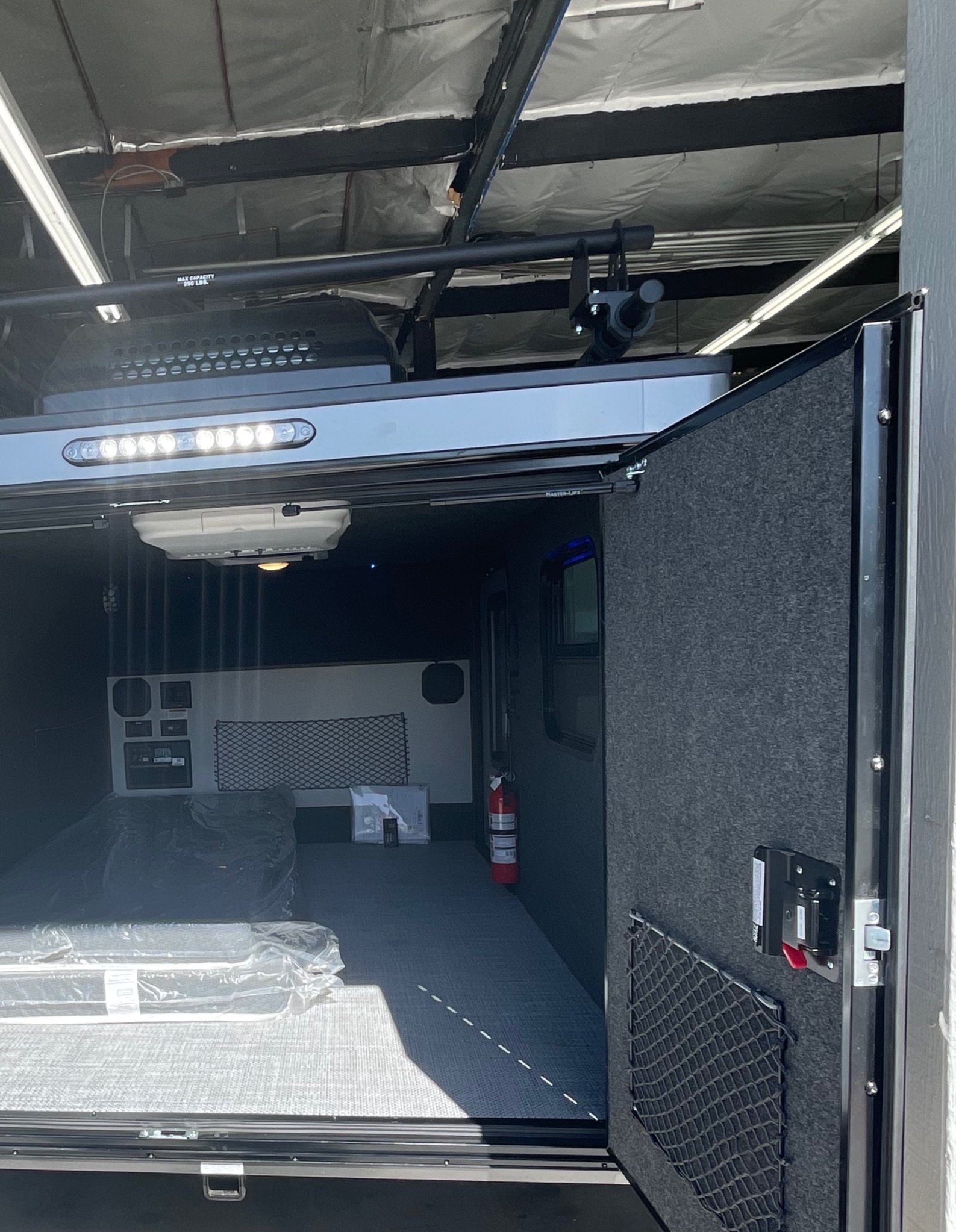 RV rental toy hauler interior: spacious cargo area with ramp door, overhead lighting, control panels, and mattress for versatile use.. InTech RV Flyer 2022