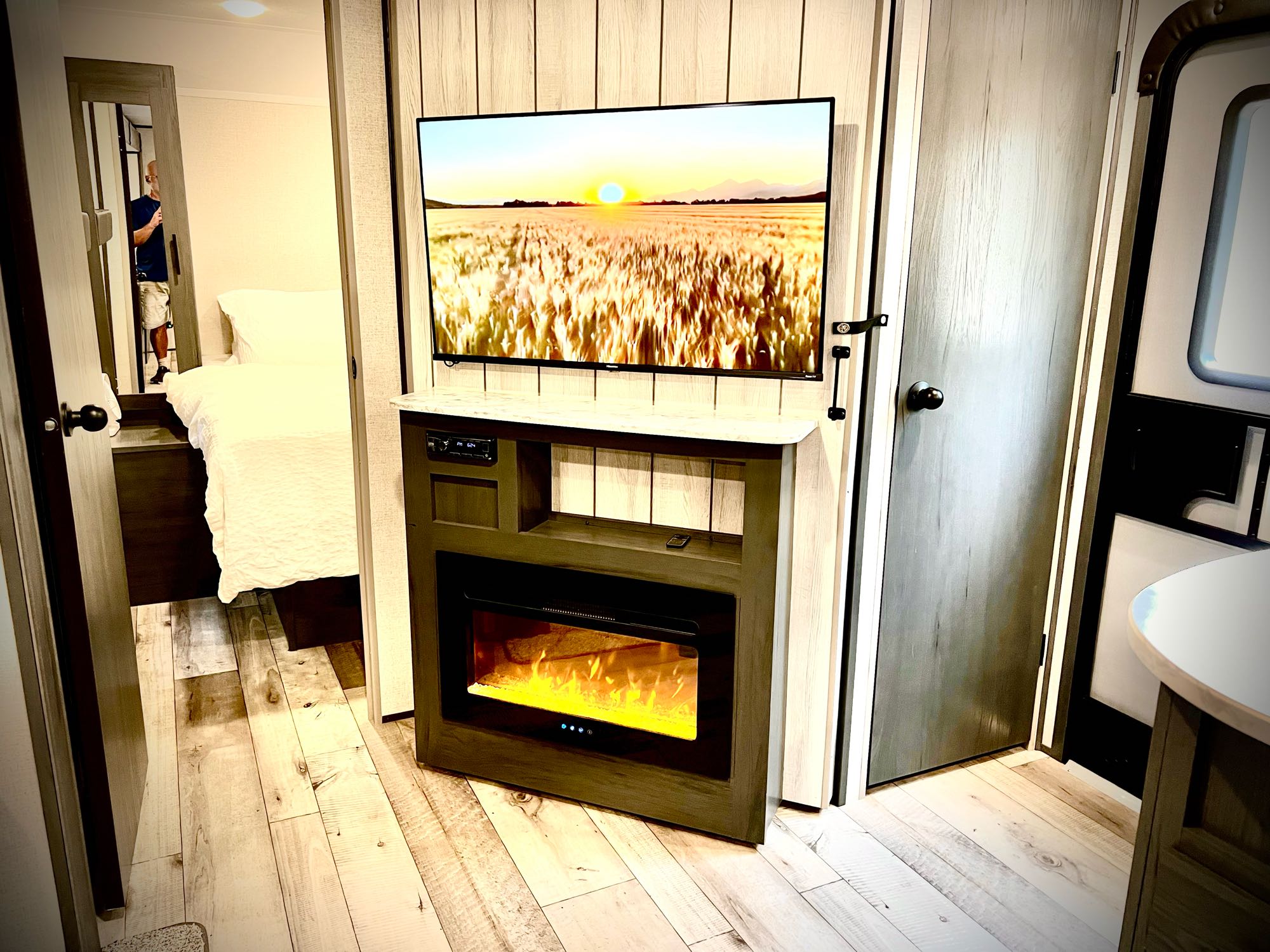 Spacious RV rental interior featuring a flat-screen TV above an electric fireplace and a bedroom entrance.. Dutchmen Colorado 2022