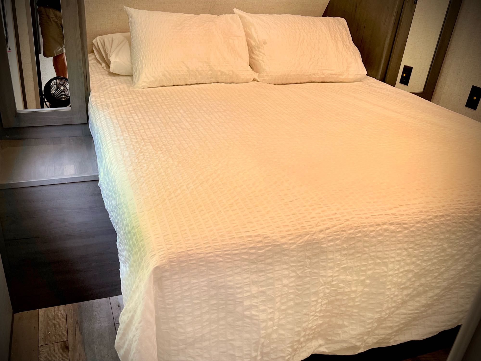 Clean, inviting RV rental bedroom. Features a neatly made white bed with textured bedding and pillows, ready for relaxation.. Dutchmen Colorado 2022