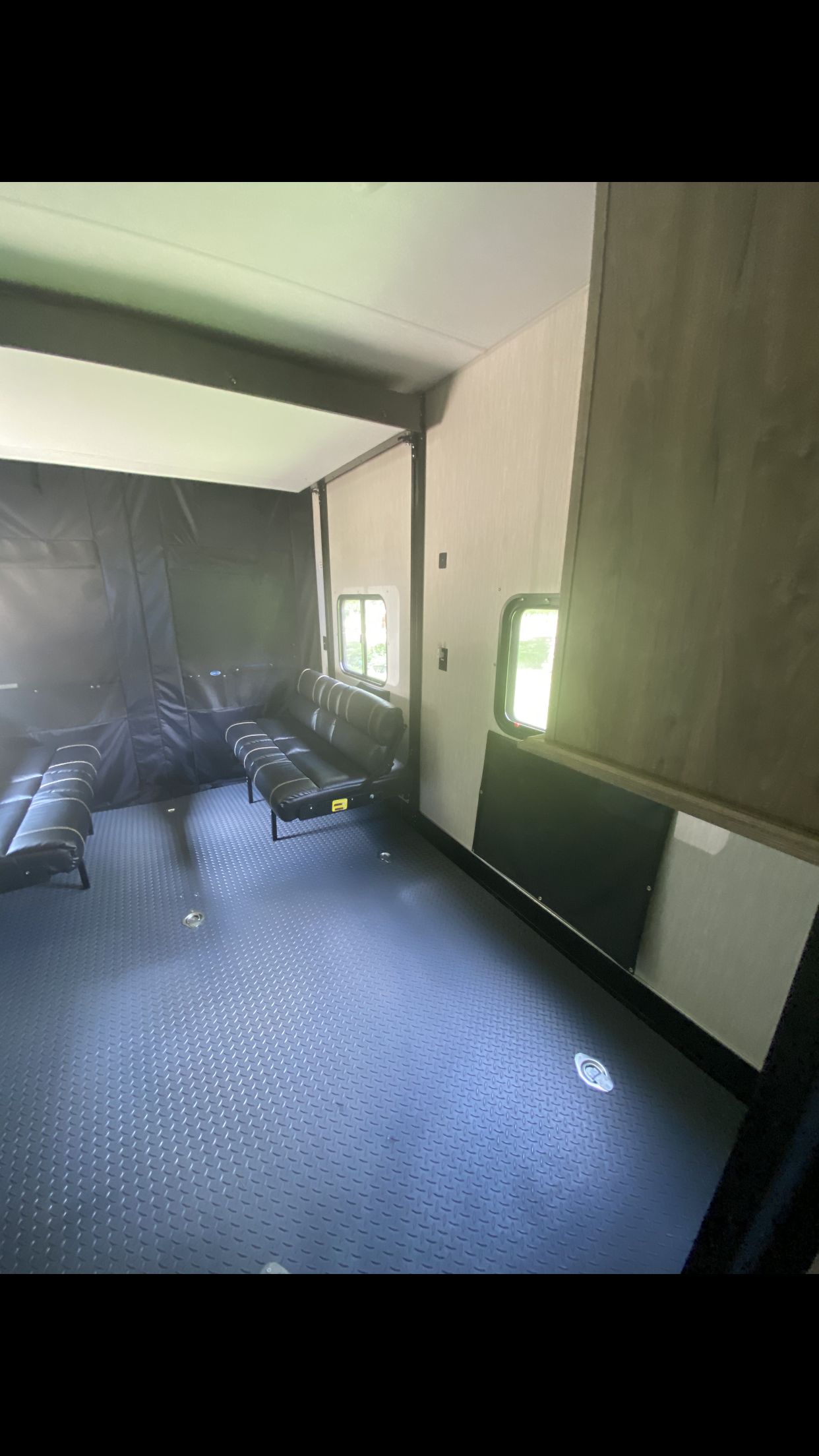 Inside an RV rental toy hauler, showing its versatile cargo area with diamond plate floor, fold-up benches, and rear access.. Forest River Cherokee Wolf Pack Toy Hauler 2020