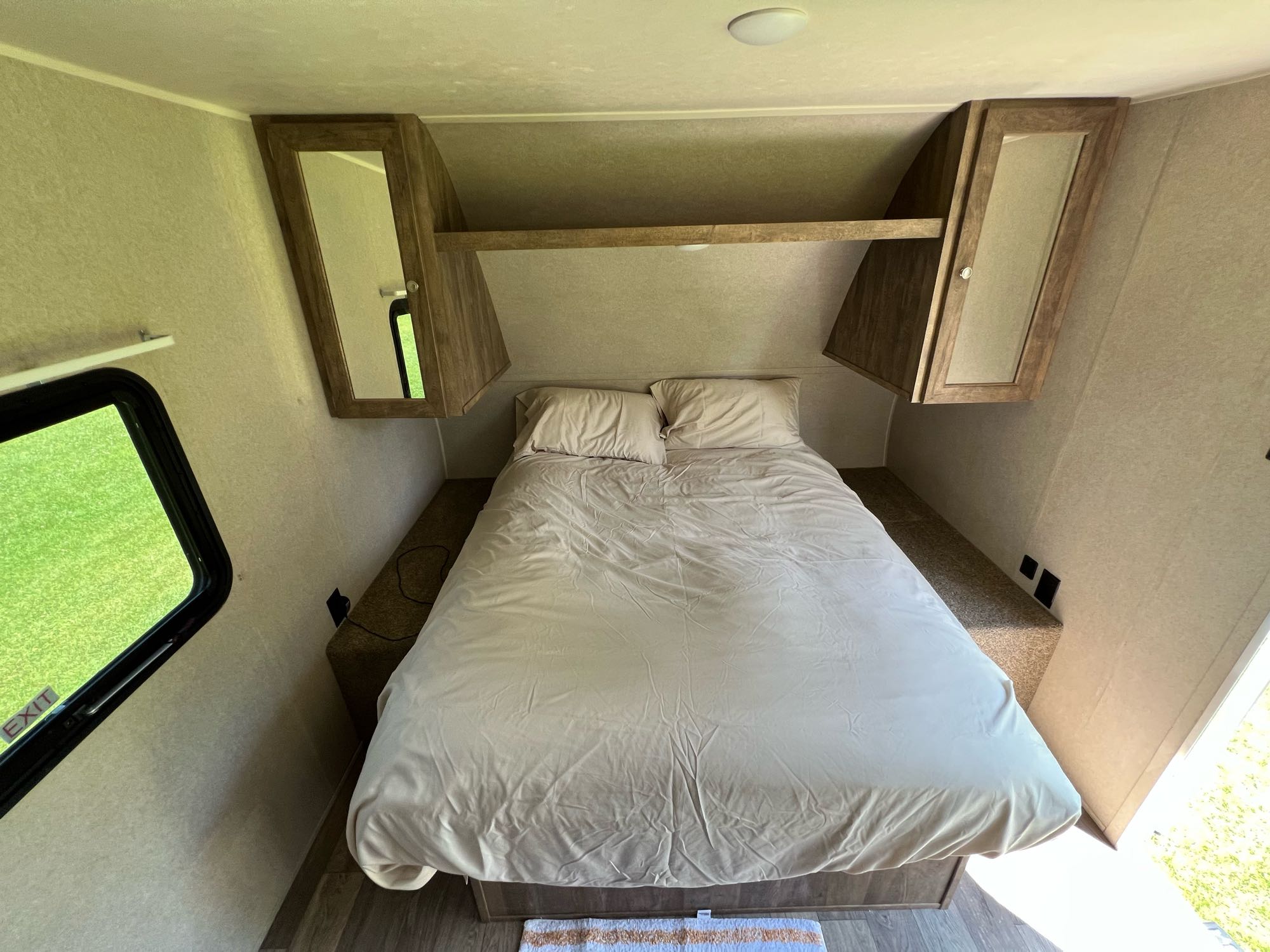 Bright RV rental bedroom with a large bed, overhead storage, and an emergency exit window for a safe journey.. Palomino Puma XLE 25 2018