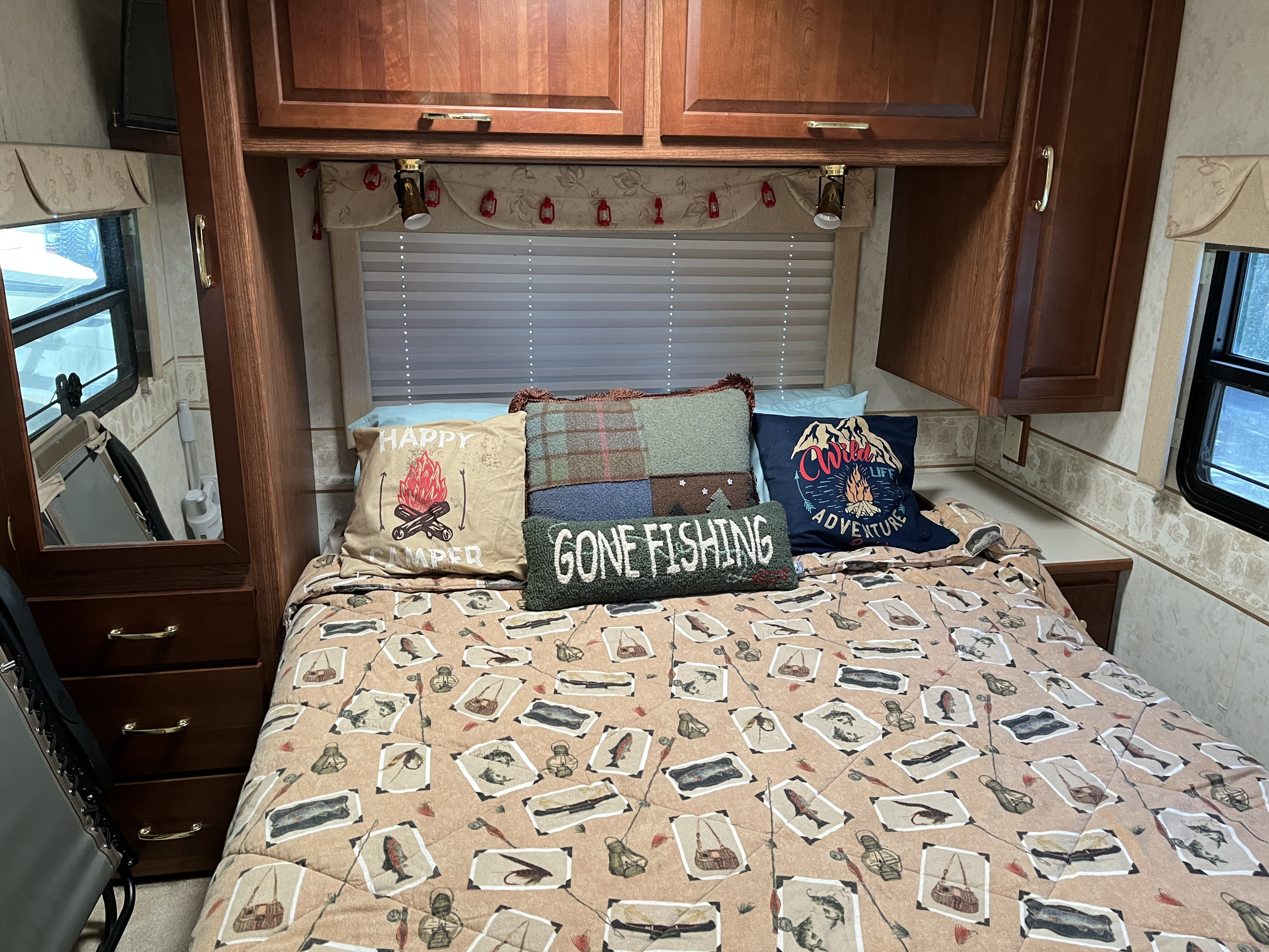 Cozy RV rental bedroom with fishing-themed comforter & camping pillows. Ideal for adventure travel.. Itasca Sundancer 2001