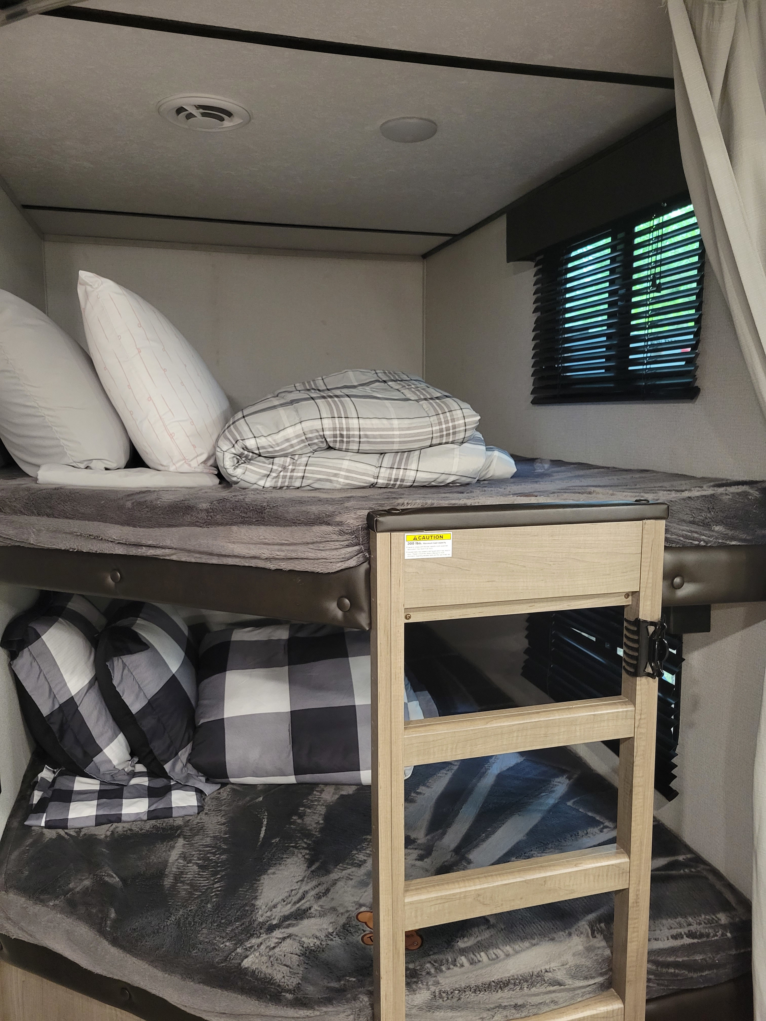 Cozy RV rental bunk beds with soft bedding and ladder, inside a travel trailer ready for family trips.. Keystone RV Hideout 2021