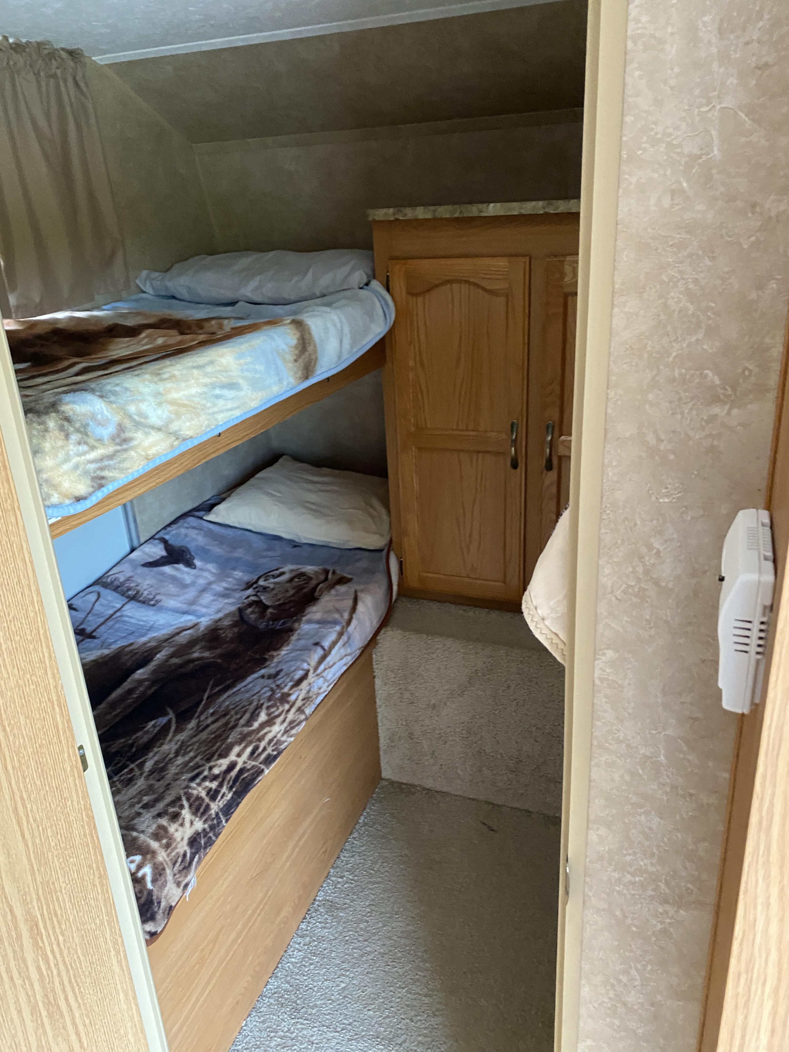 Inside an RV rental: cozy bunk beds with themed blankets, a storage cabinet, and carpeted floor provide comfortable sleeping space.. Keystone RV Springdale 2010