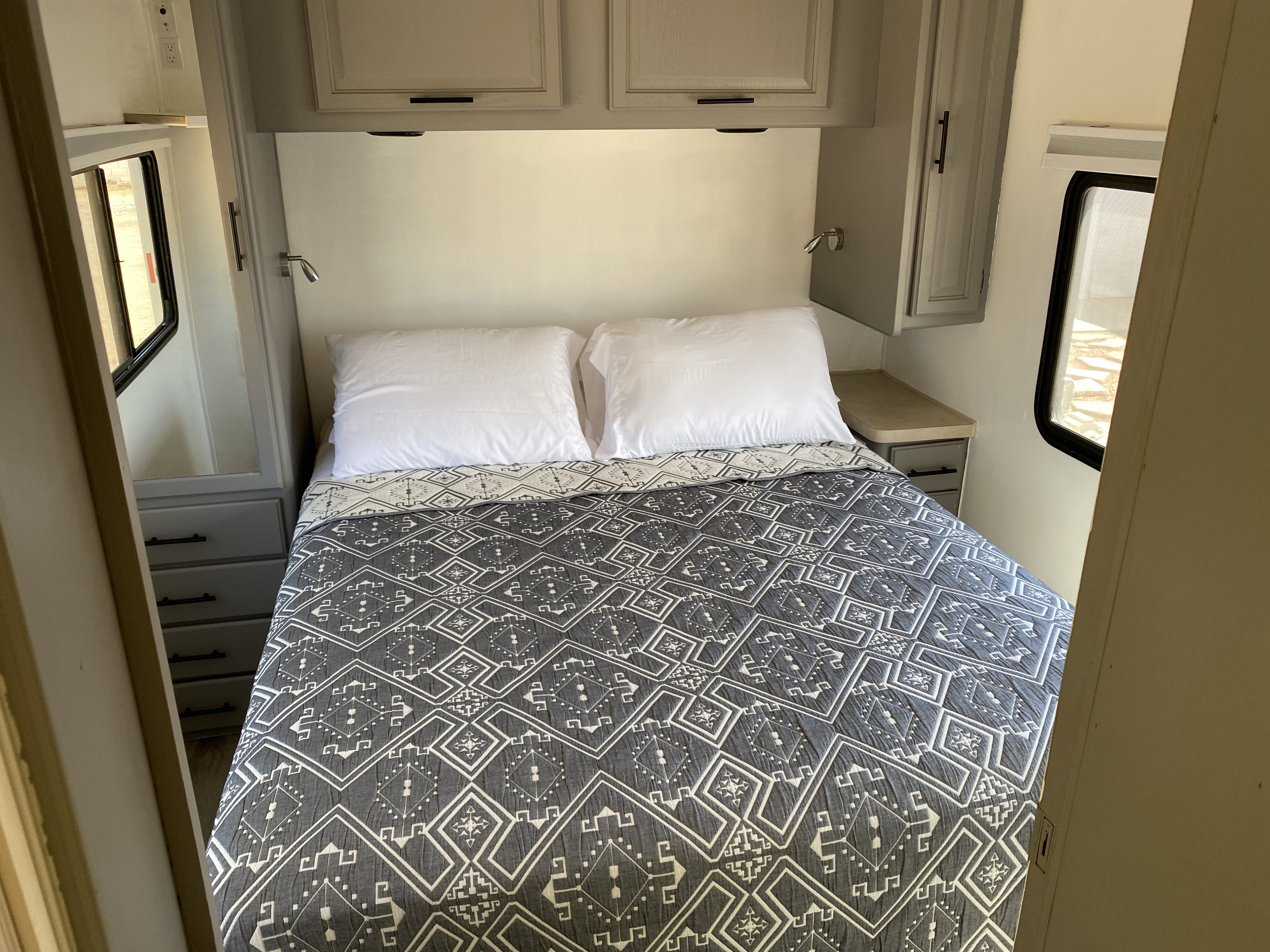 Cozy RV rental bedroom: full bed with a modern gray quilt, overhead cabinets, and convenient side storage.. Flair-Fleetwood Flair-Fleetwood Motorhome 2004