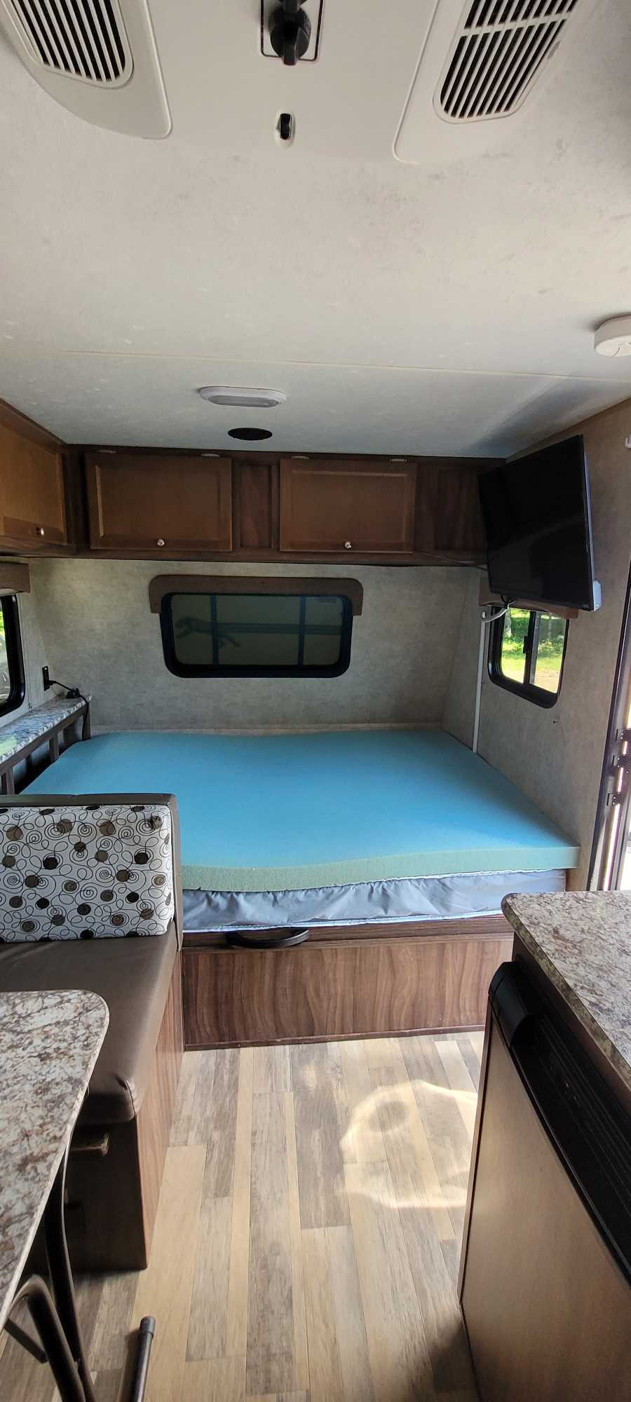 Inside an RV rental: Cozy living space with a bed, dinette, kitchen counter, and wall-mounted TV.. Coachmen Clipper 2018