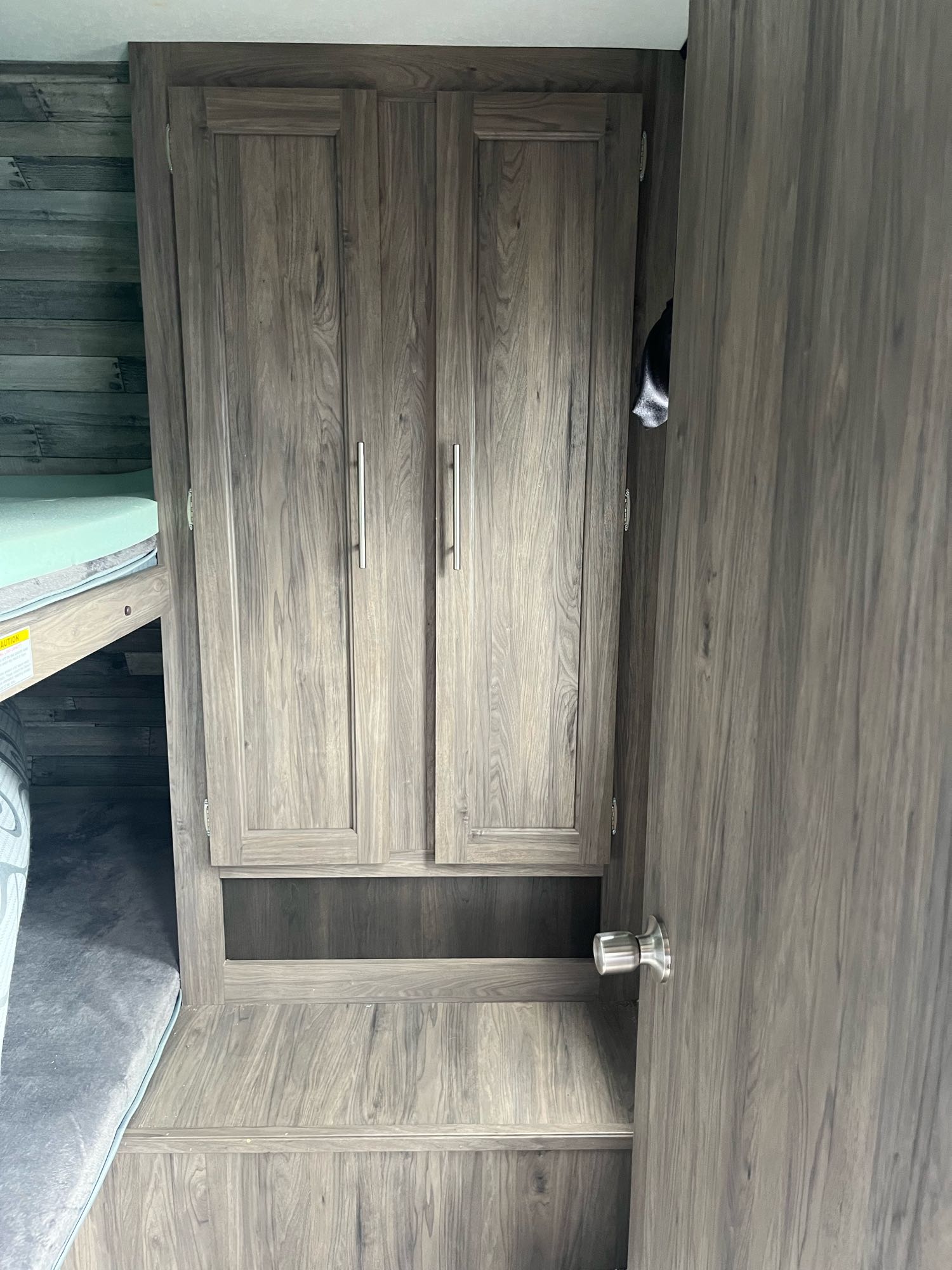 RV rental bedroom showcasing wood-look bunk beds, built-in storage cabinets, and a nearby door.. Crossroads RV Zinger 2020