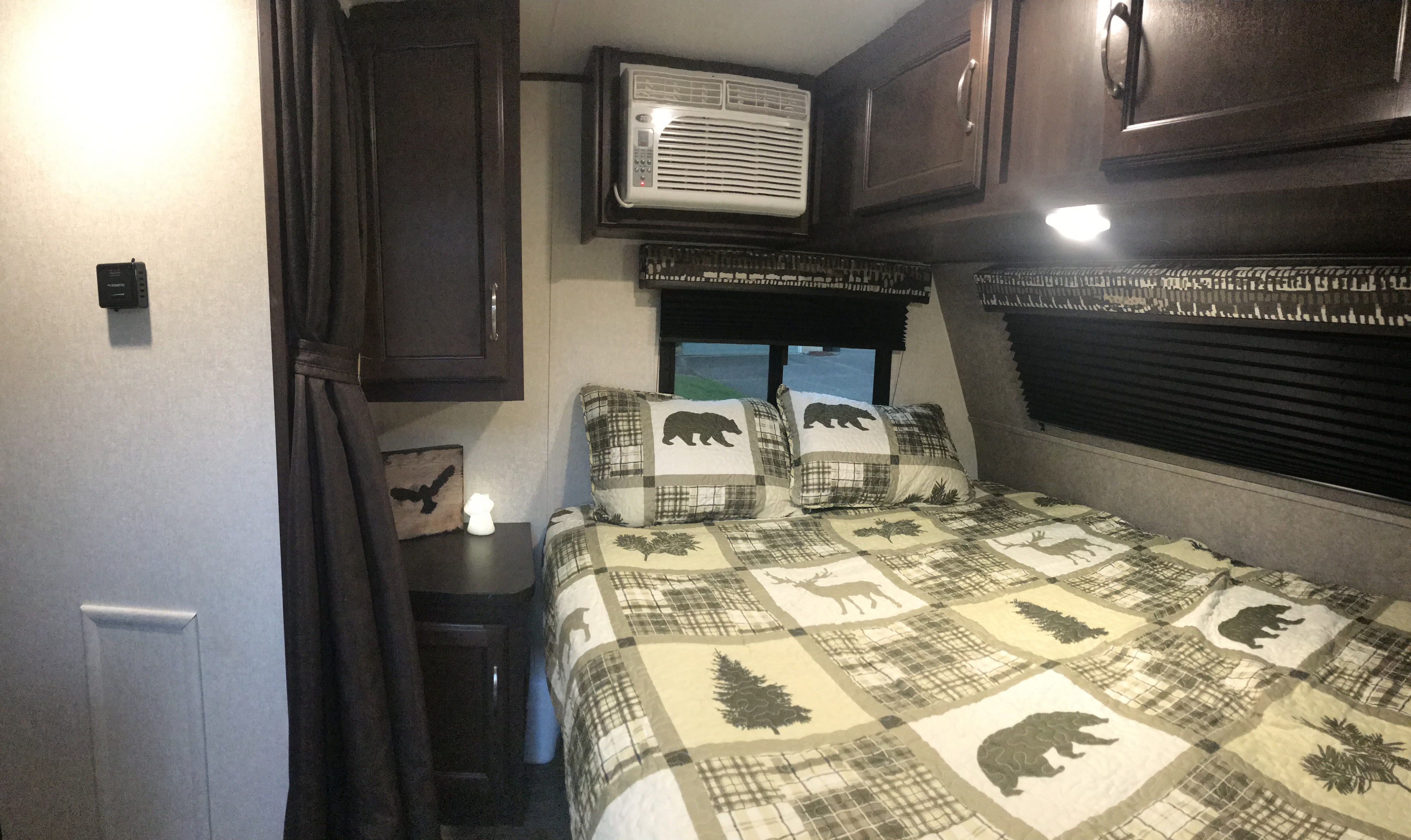 Cozy RV rental bedroom with wildlife-themed bedding, wall AC, and dark wood cabinets.. Jayco Jay Flight SLX Baja Edition 2018