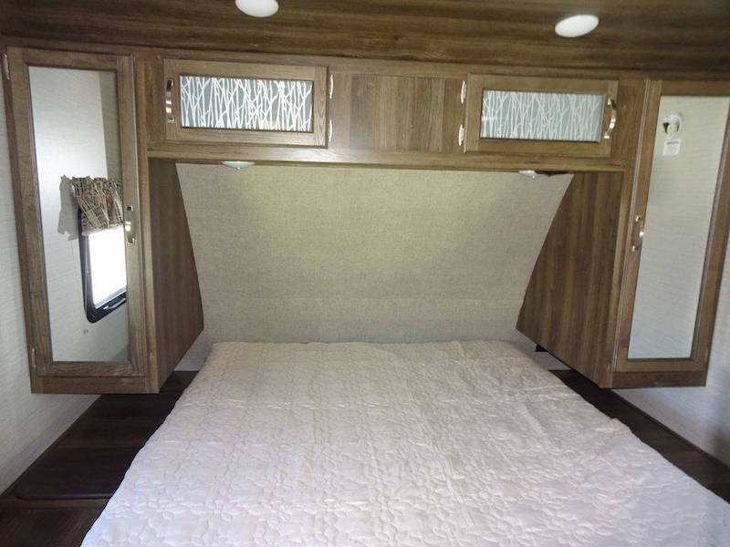 Cozy RV rental bedroom with a comfy bed, wood-grain cabinets, and compact storage. Ready for your adventure.. Keystone RV Premier UltraLite 29RKPR 2021