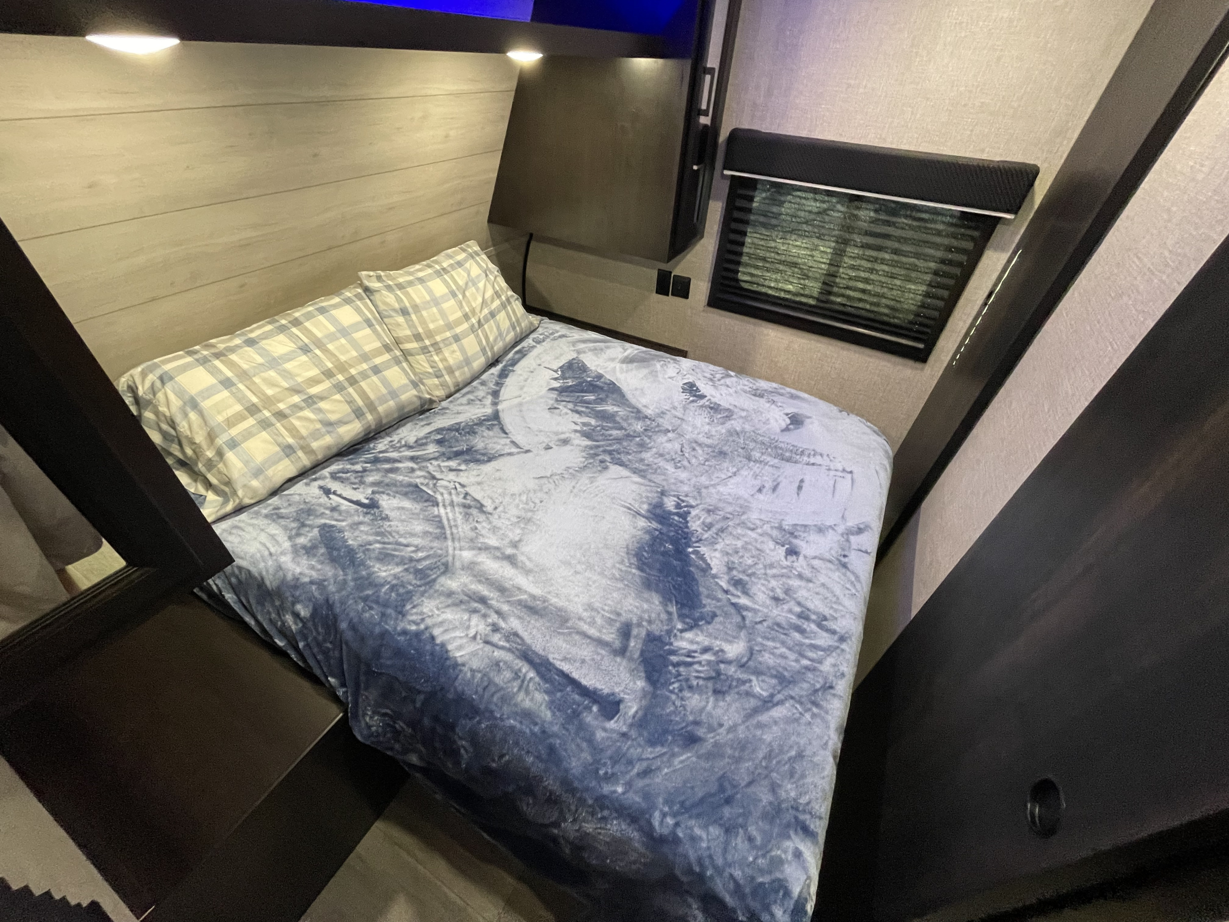 Cozy RV rental bedroom with plaid pillows and a blue wolf-themed blanket.. Jayco Jay Flight 2022