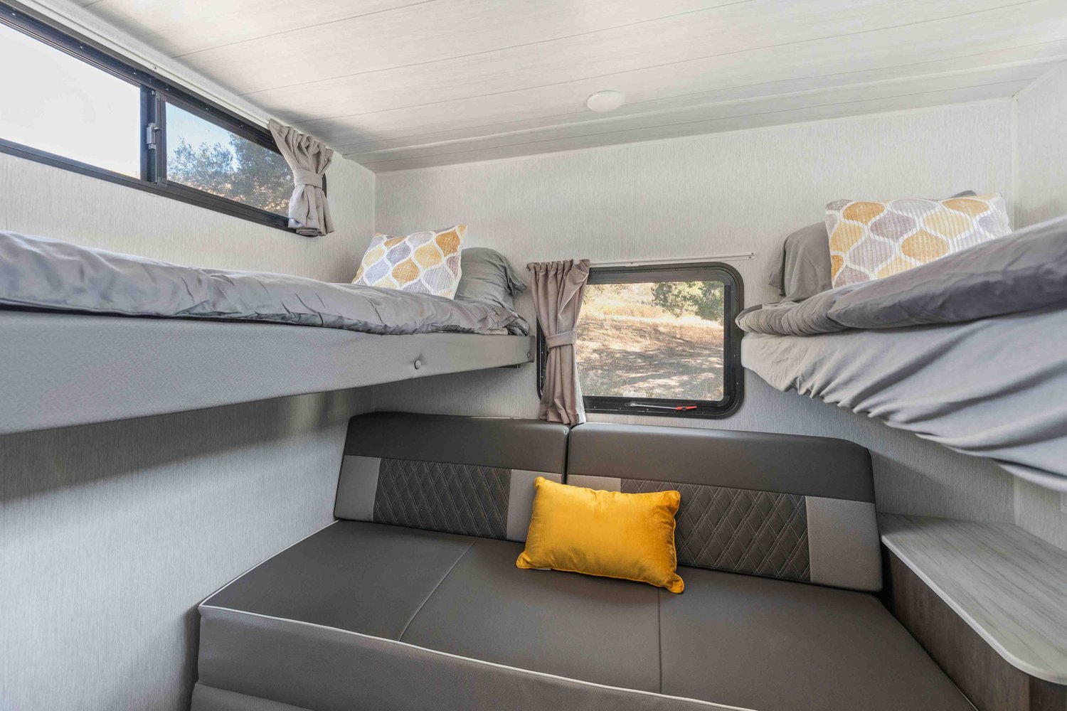 Cozy RV rental interior: Features comfy bunk beds with grey bedding, a modern sofa below, and bright windows. Perfect for adventures.. Forest River Salem Cruise Lite 2022