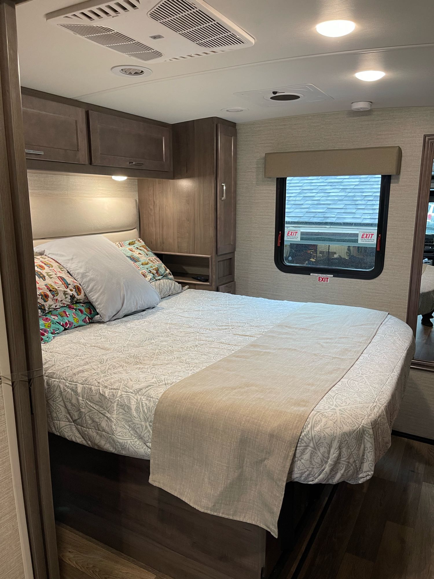 Cozy RV rental bedroom with a comfy bed, overhead storage, and an emergency exit window.. Winnebago Vista 2022