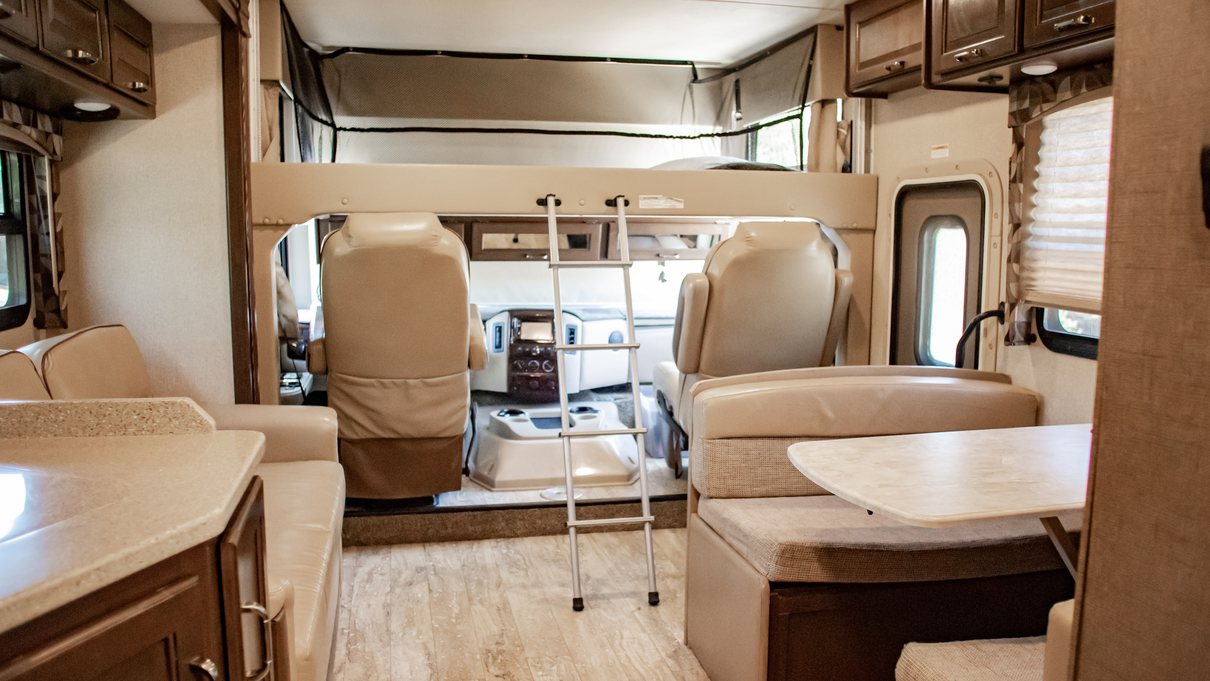 Spacious RV rental interior showcasing an overhead bunk, dinette, and kitchen area. Perfect for family adventures.. Thor Hurricane 2017