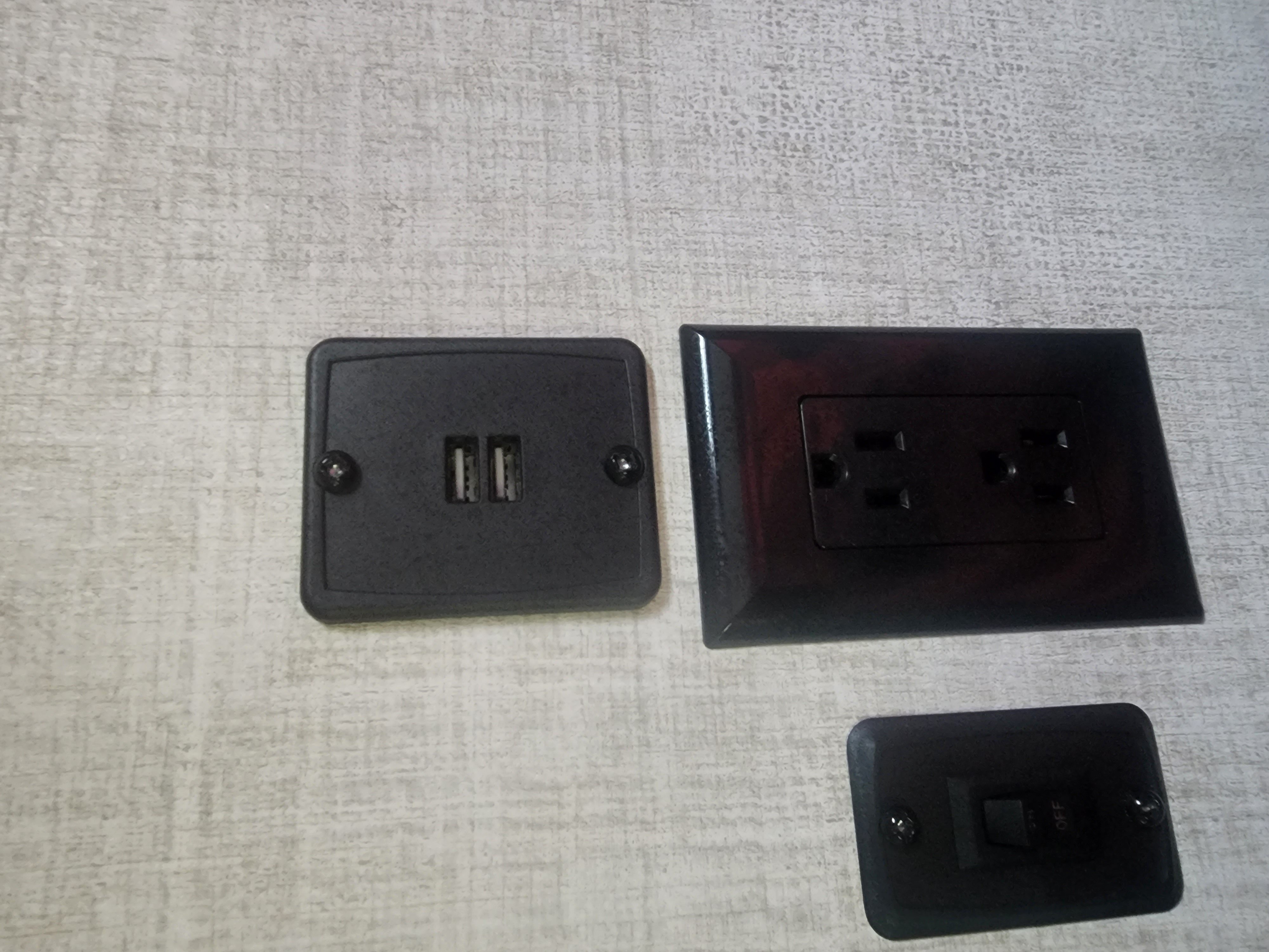 Power convenience in an RV rental: dual USB ports, two AC outlets, and a light switch on a textured wall.. Gulf Stream Kingsport 2022