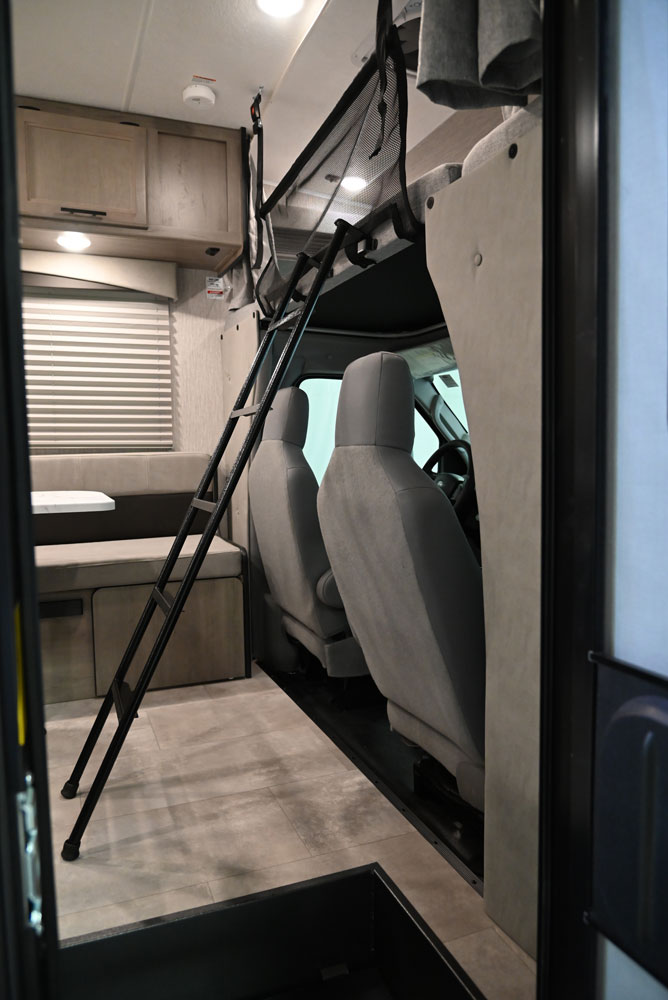 Inside an RV rental: view from entry towards the front, showing overhead bunk with ladder, cab seats, and dinette. Ideal for travel.. Forest River Coachmen Cross Trail XL 2022