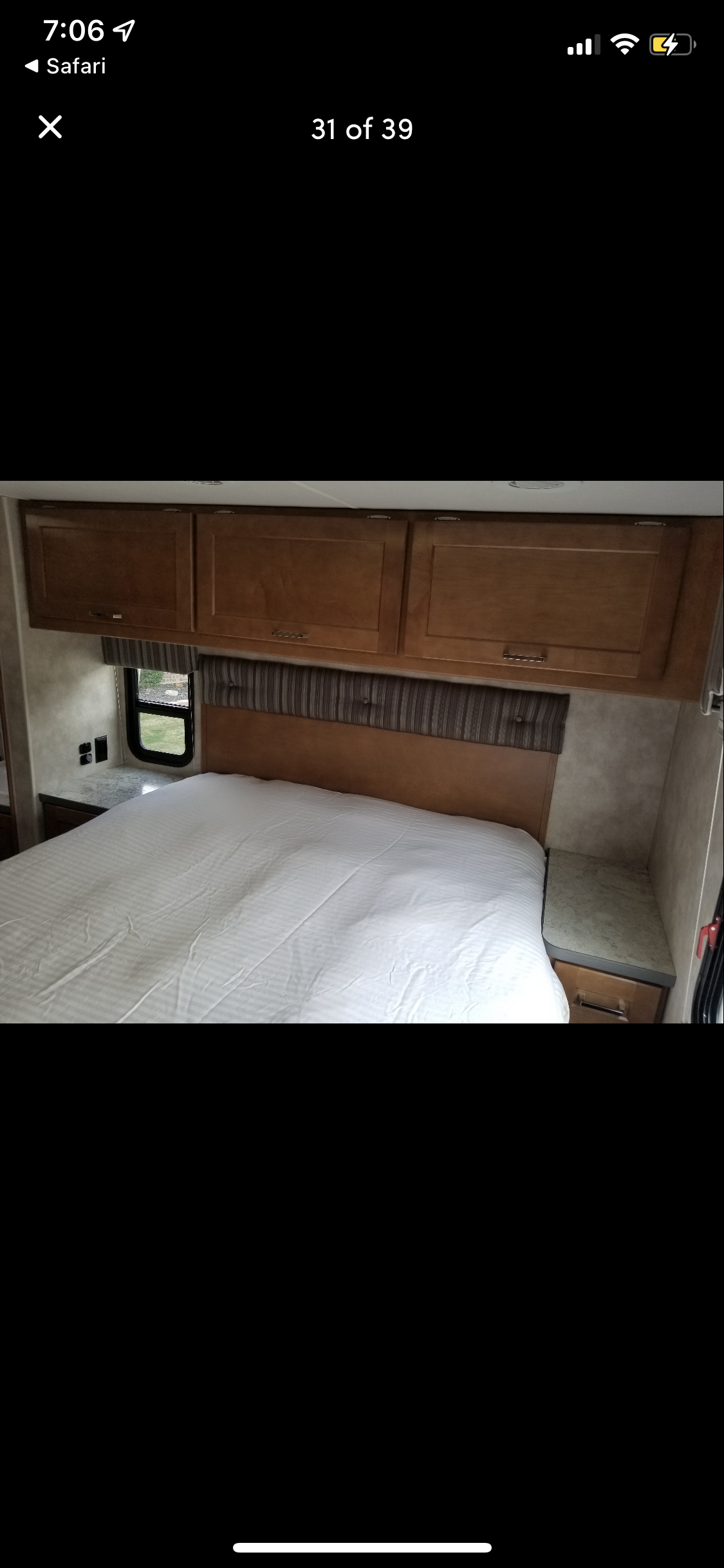 RV rental bedroom interior: Features a neat bed with overhead wooden cabinets and a side window.. Winnebago Minnie Winnie 2019