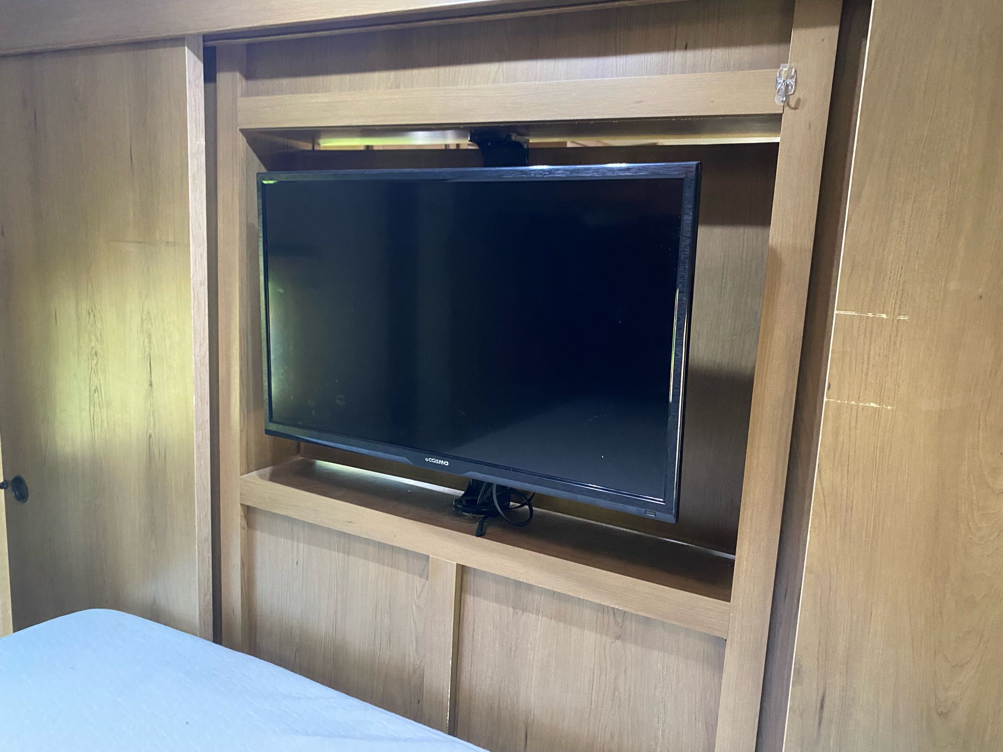 RV rental interior: A TV mounted in a light wood entertainment unit with shelving. Bed and sliding doors are visible.. Cruiser Rv Corp 280Bunkhouse Cruiser 2015