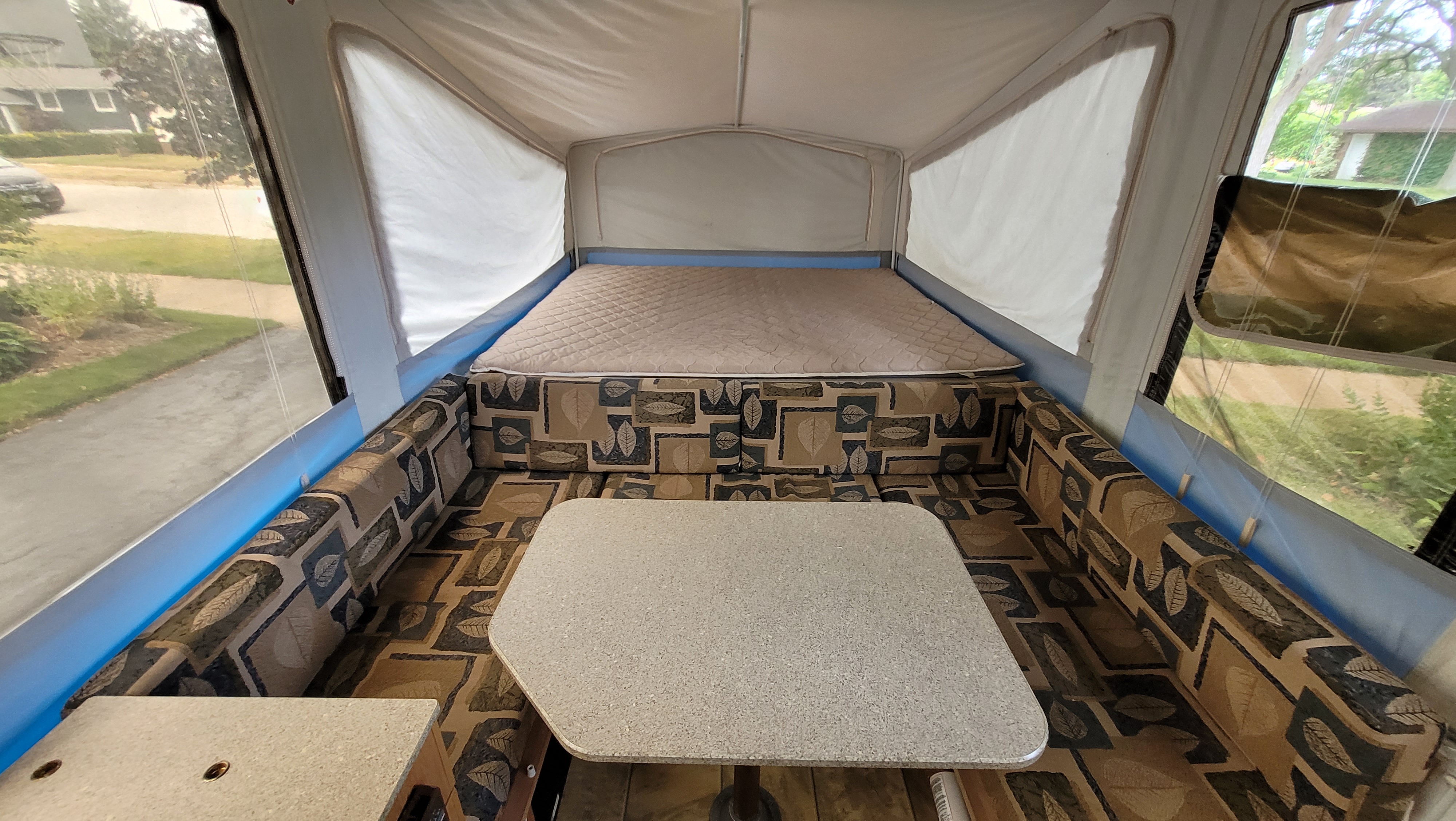 Pop-up camper RV rental interior: featuring a cozy bed, a U-shaped dinette, and bright windows.. Jayco 1207 2008