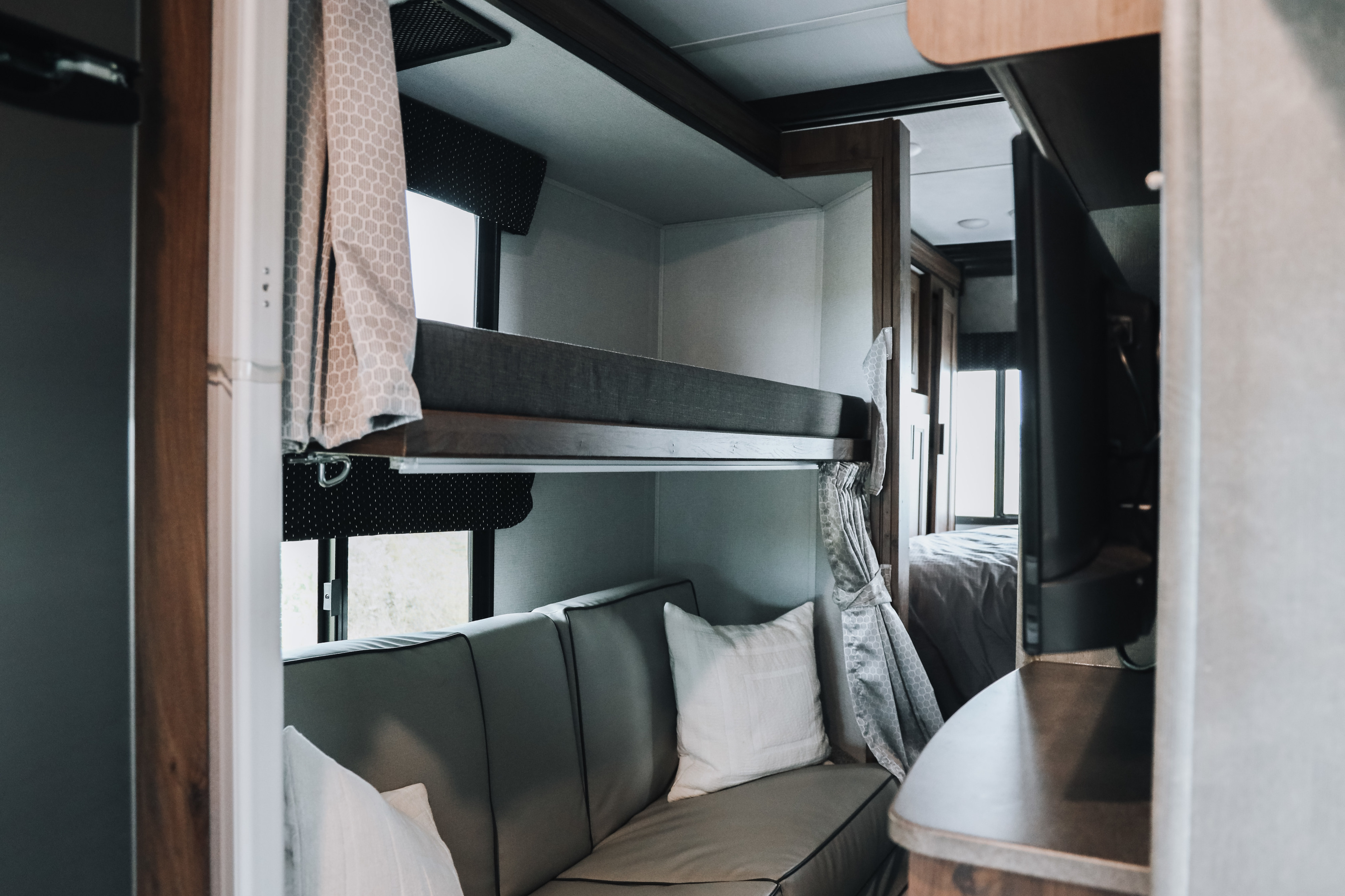 This RV rental interior features comfortable bunk beds over a sofa, with a glimpse of the main bedroom beyond.. Forester LE 2021