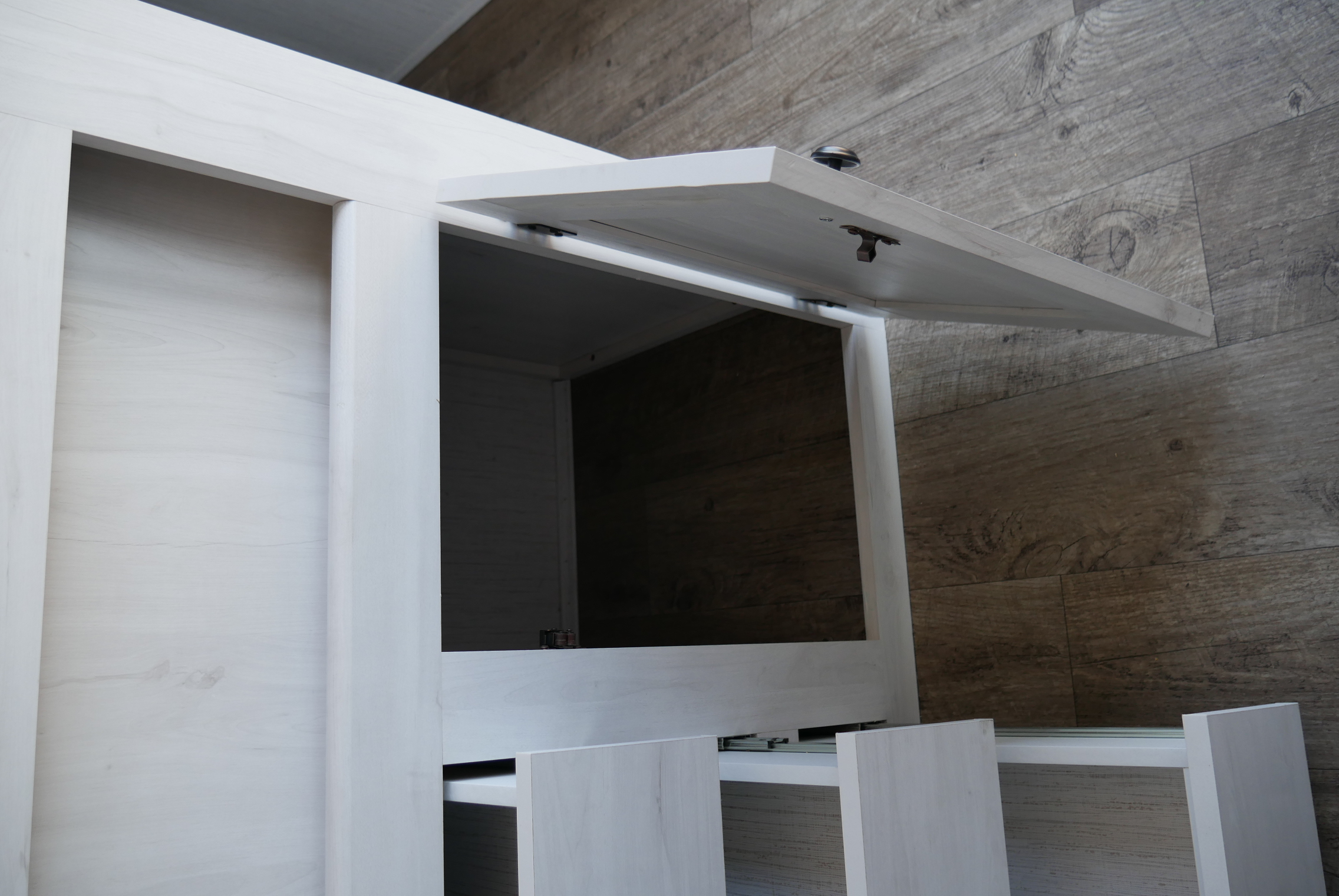 RV rental interior: light wood cabinet with an open top compartment and pull-out drawers, showing compact storage.. Heartland RVs Trailrunner 2021