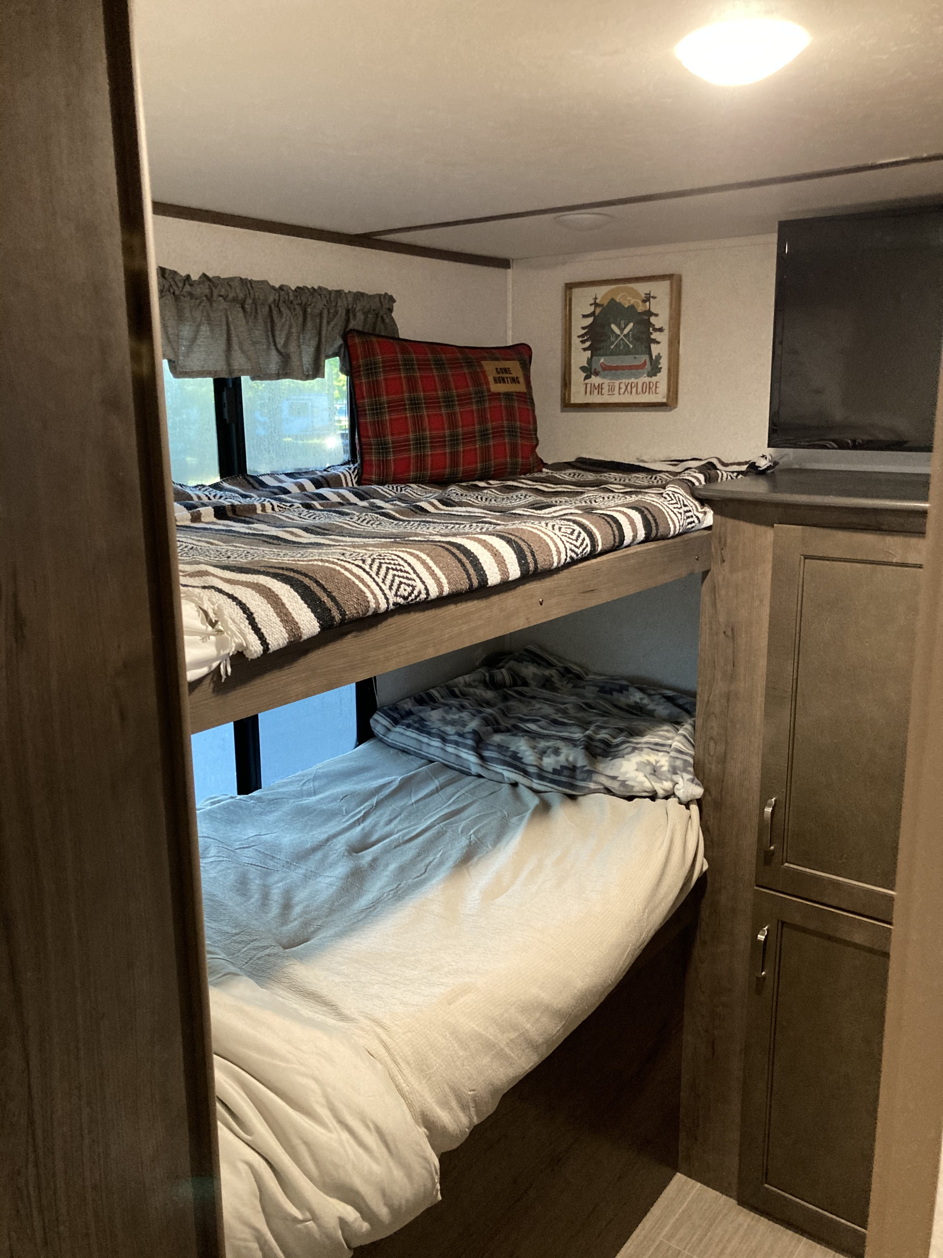Cozy RV rental interior showcasing comfortable bunk beds with patterned blankets, perfect for family travel adventures.. Keystone RV Passport SL 2020