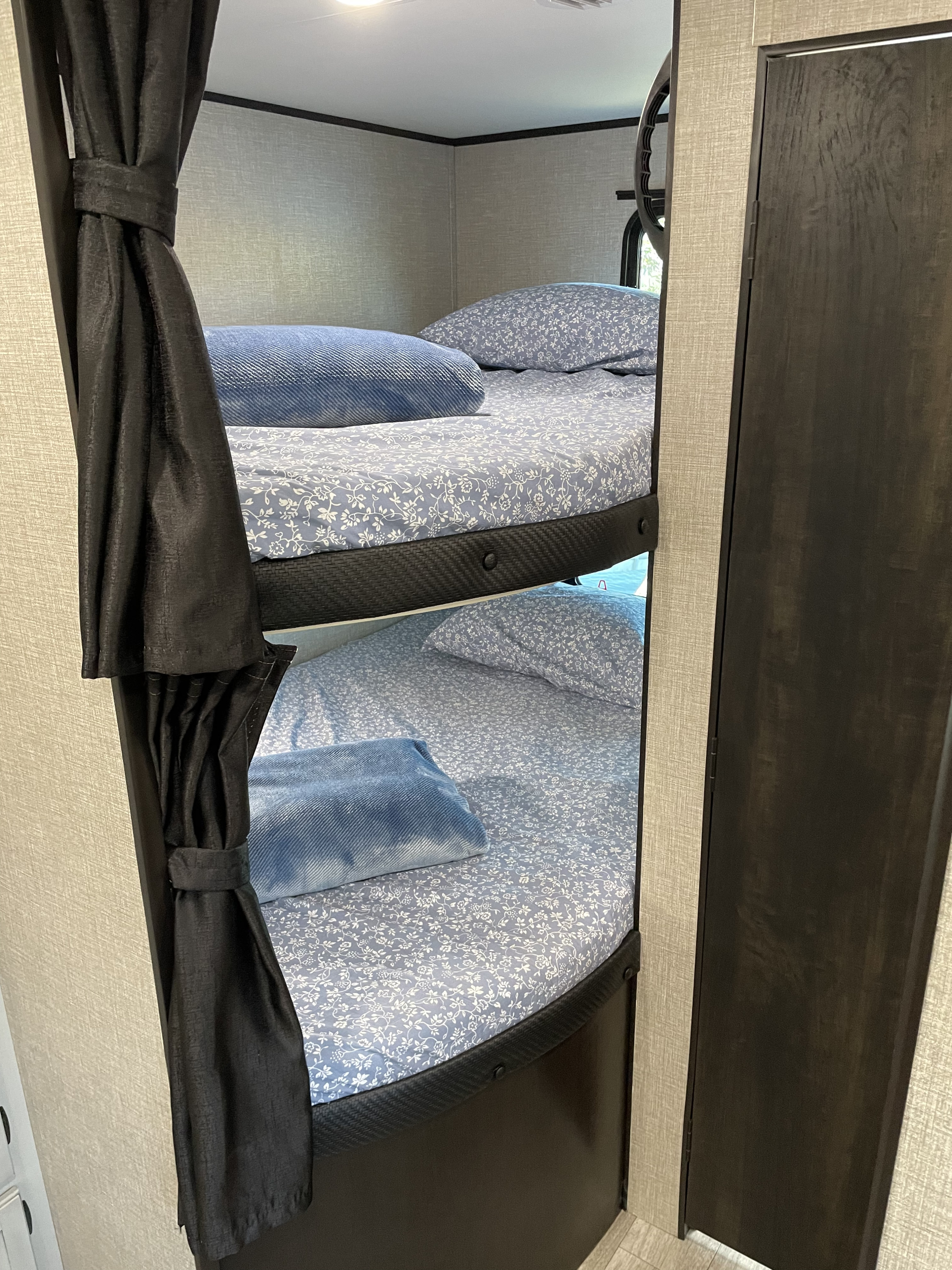 Cozy bunk beds in an RV rental, perfect for family adventures. Features floral sheets and privacy curtains.. Jayco Jay Flight 2022